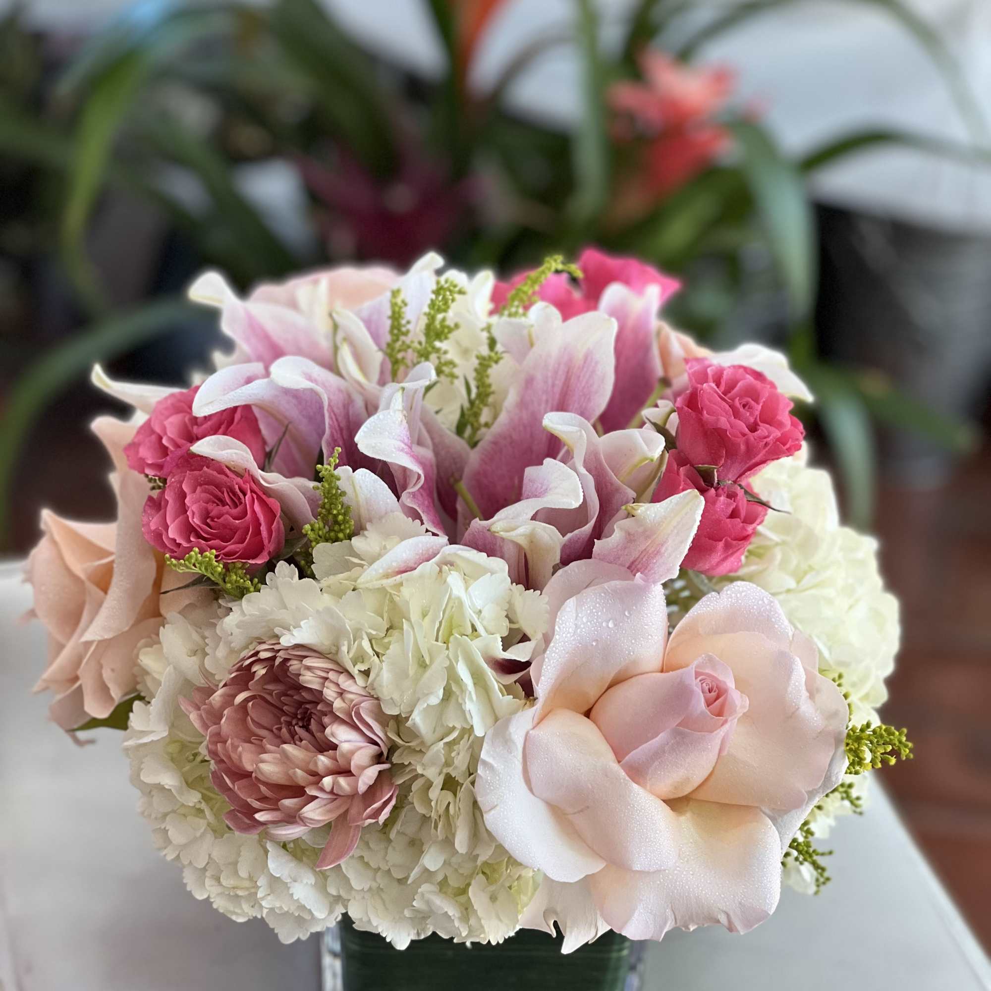 Pink and white floral arrangement in a square glass vase