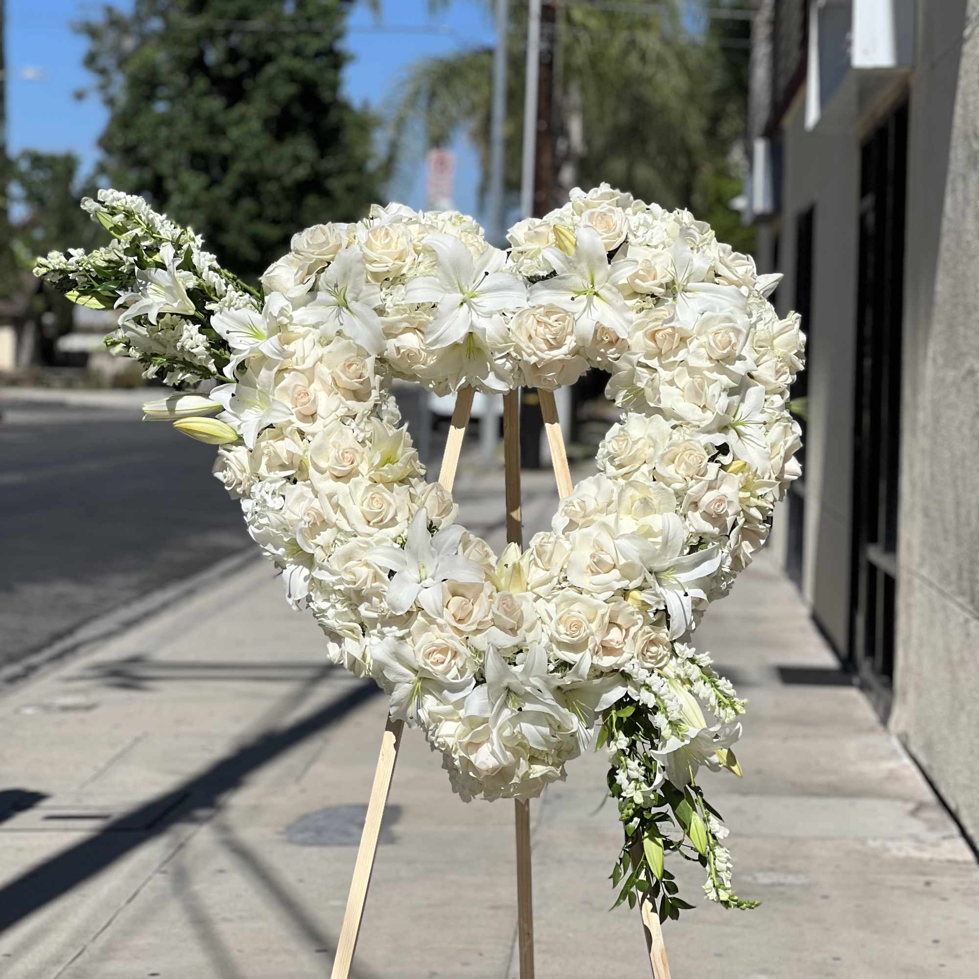 Heart-shaped white floral standing arrangement on an easel