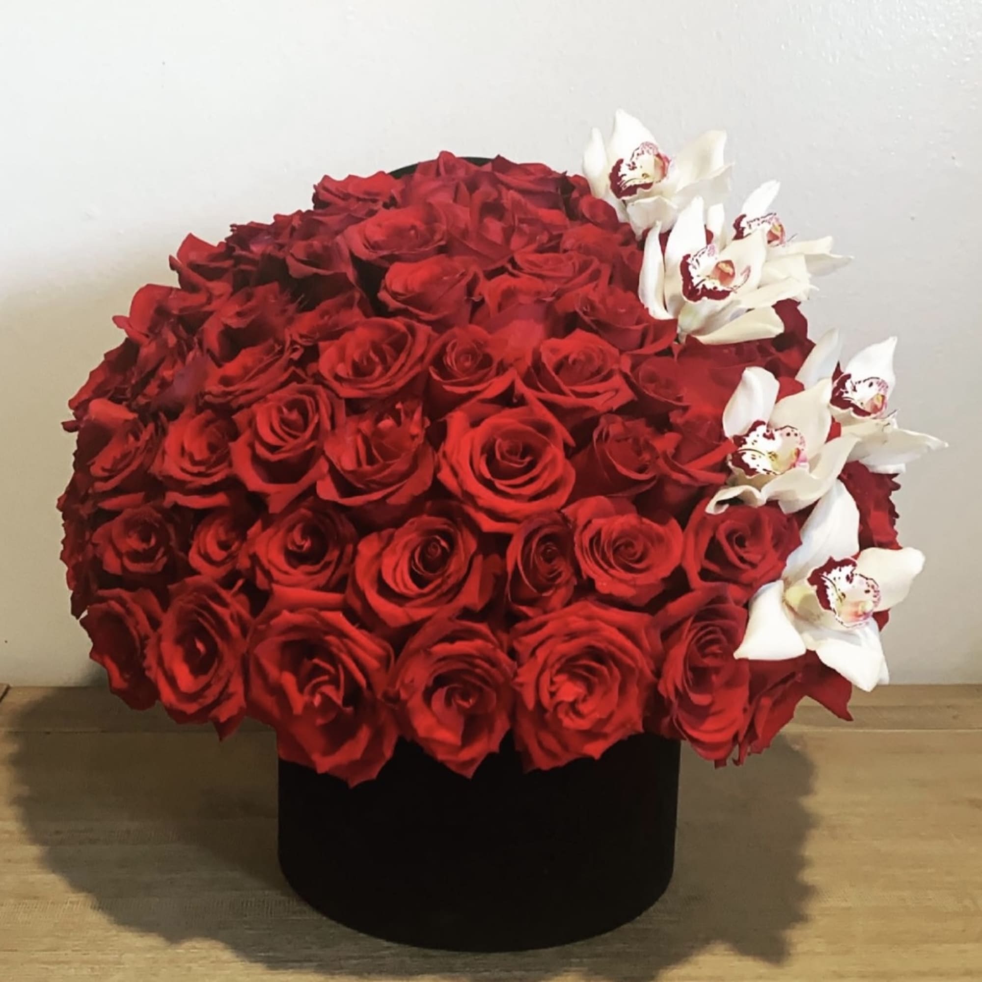 Red rose arrangement with white orchids in a black box