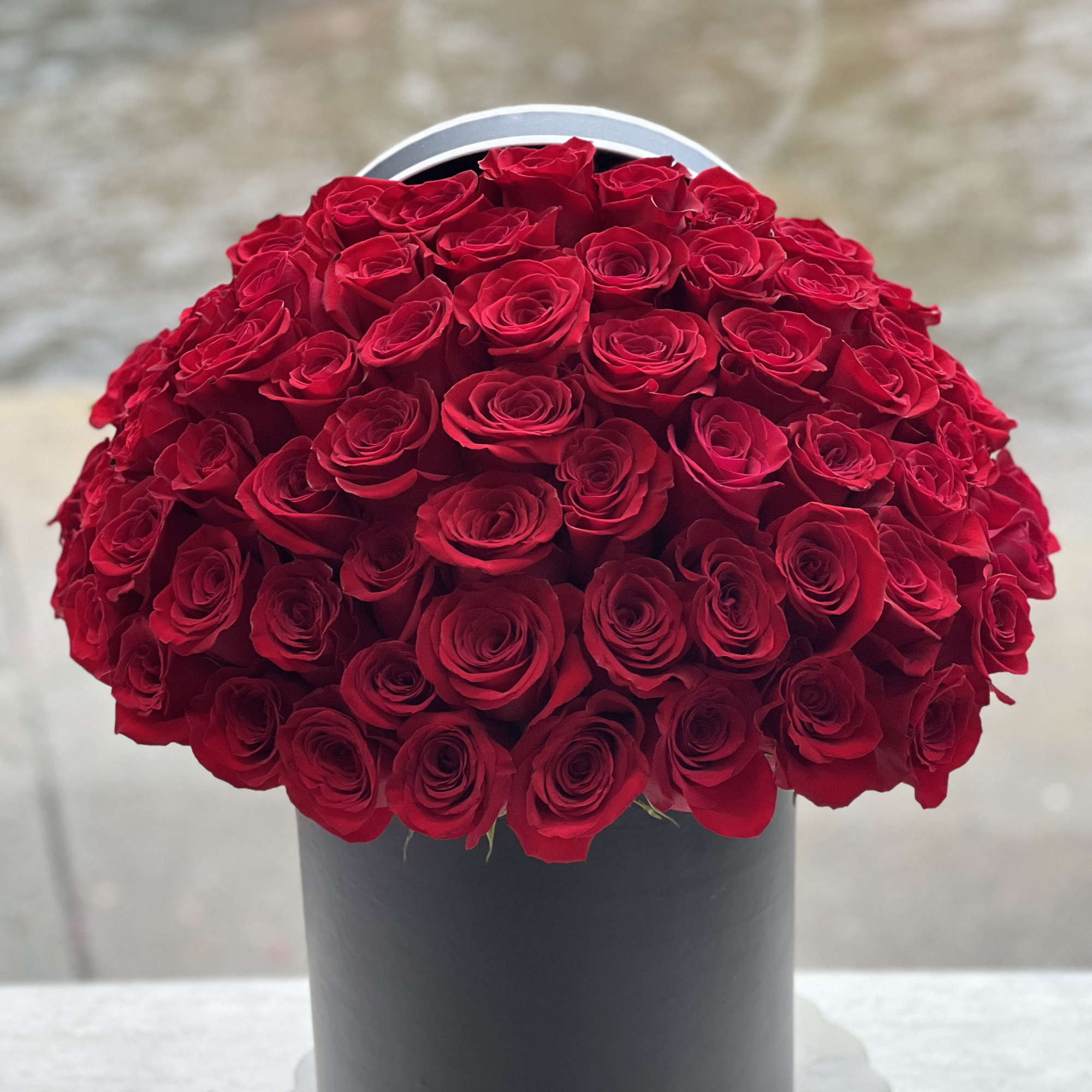 Large bouquet of red roses in a black hatbox