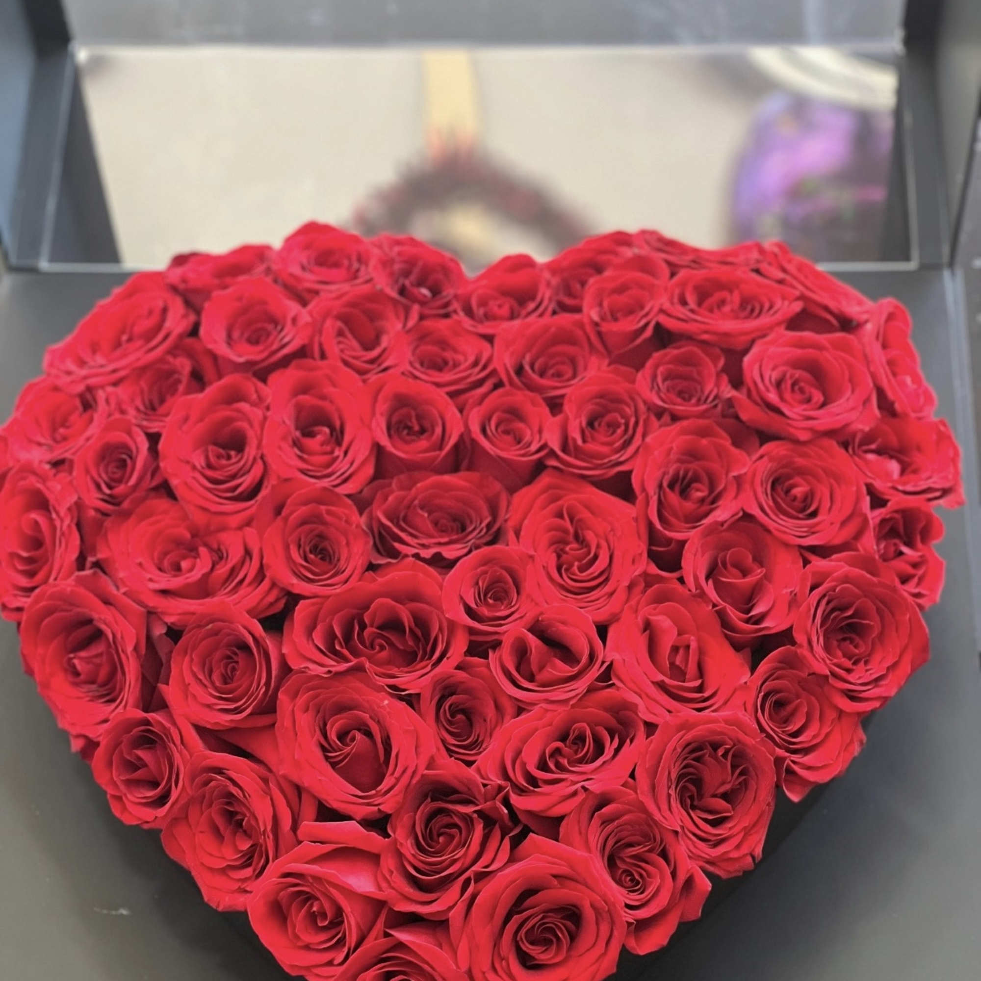 Heart-shaped arrangement of red roses in a black box