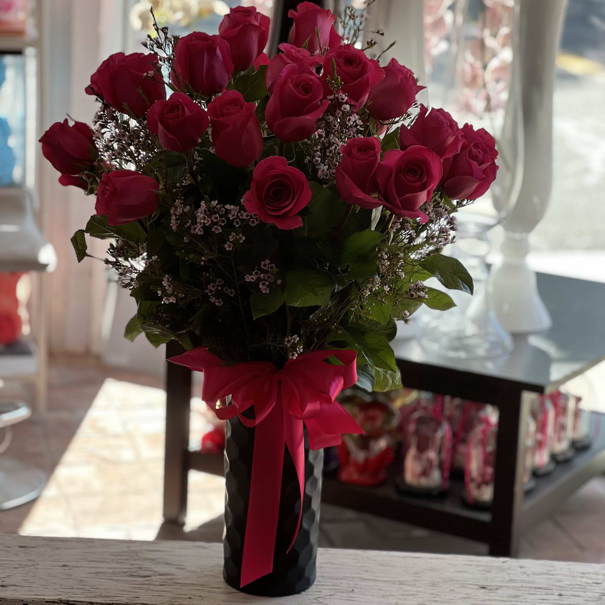 Bouquet of hot pink roses in a black vase with a pink ribbon