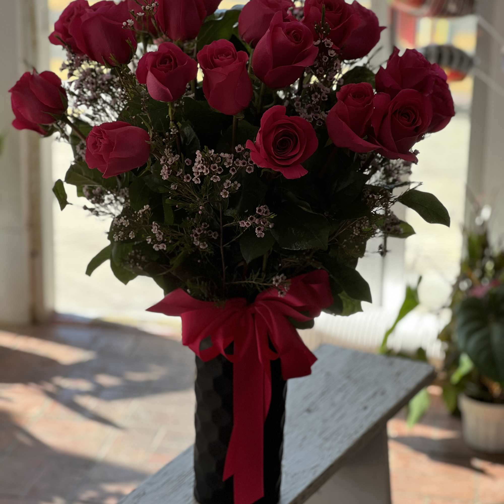 Bouquet of red roses in a black vase with a red ribbon