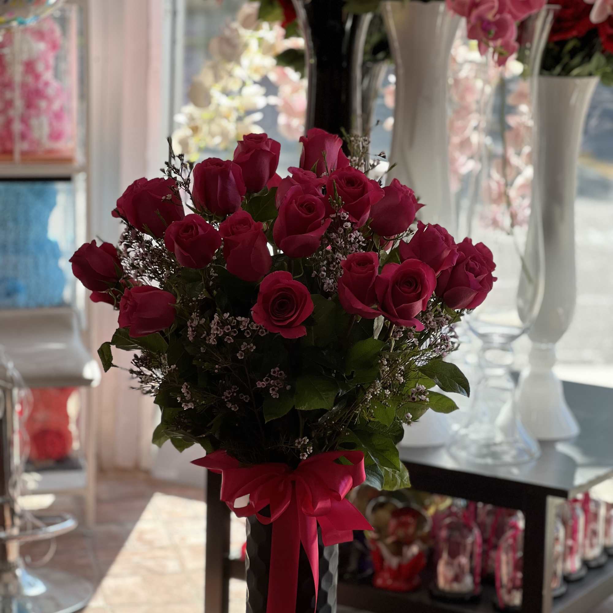 Bouquet of red roses in a black vase with a pink ribbon
