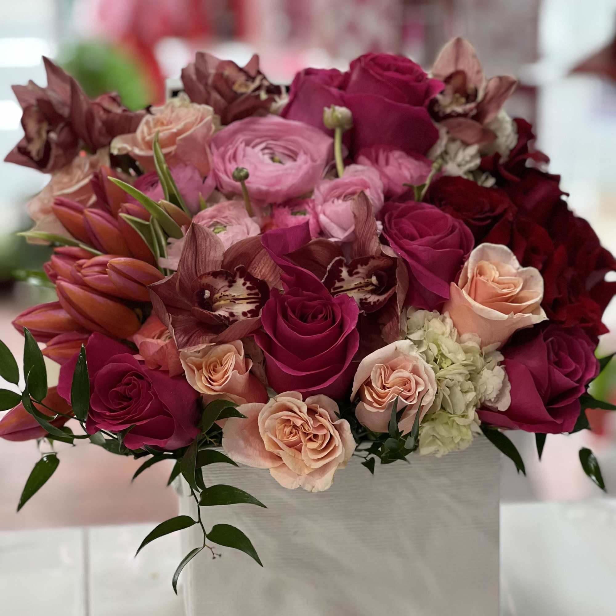 Pink and magenta roses with orchids in a white box