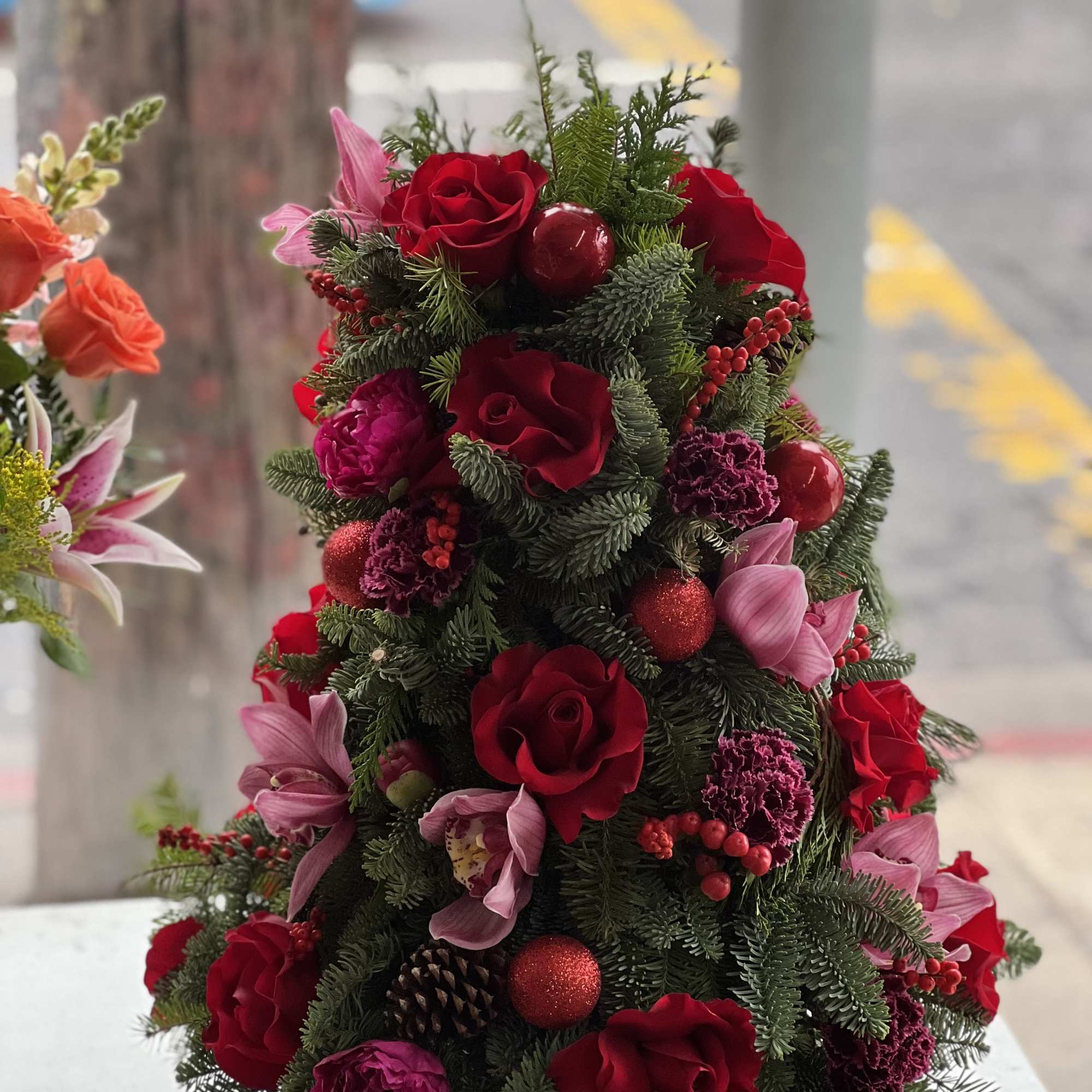 Christmas tree-shaped floral arrangement with red roses and pink blooms