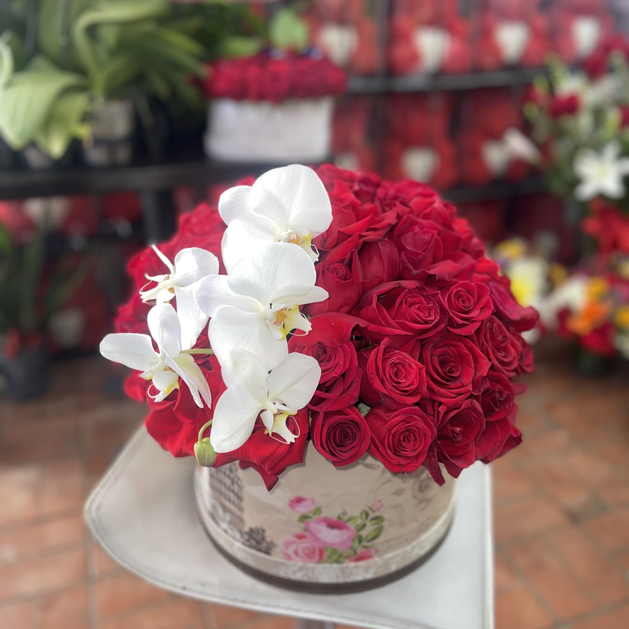Red rose arrangement with white orchids in a round box