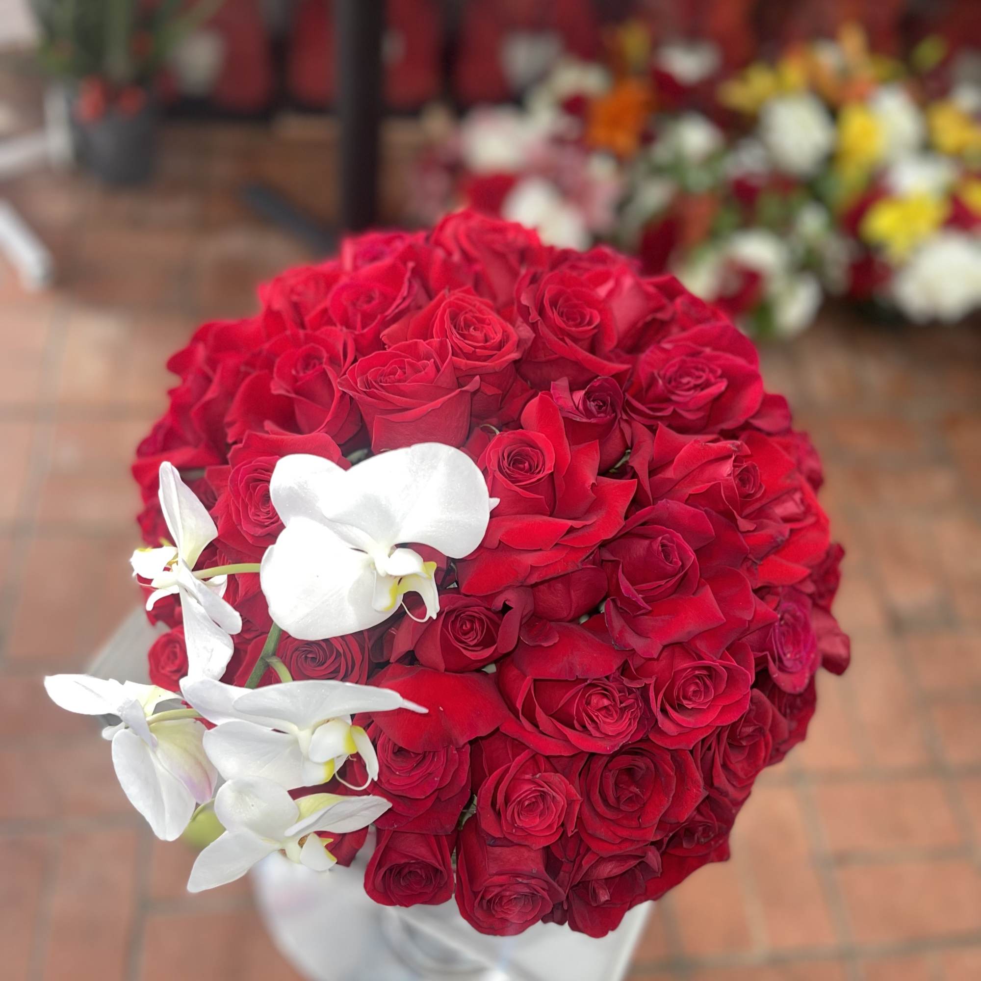 Round bouquet of red roses with white orchids