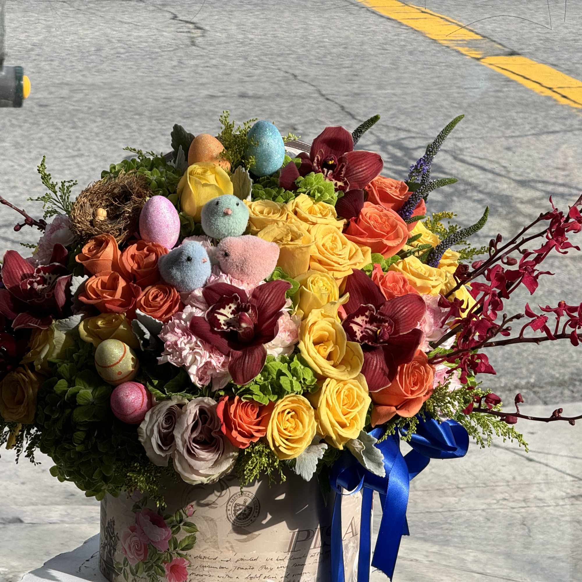 Colorful bouquet of roses and orchids with decorative Easter eggs in a box