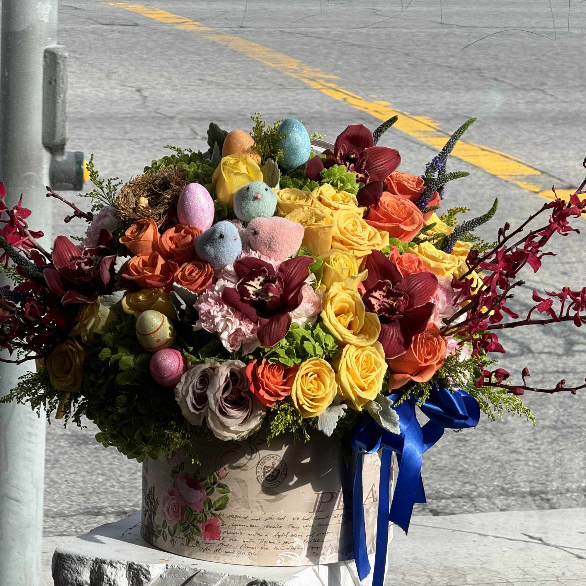 Colorful bouquet of roses and orchids in a decorative box with blue ribbon