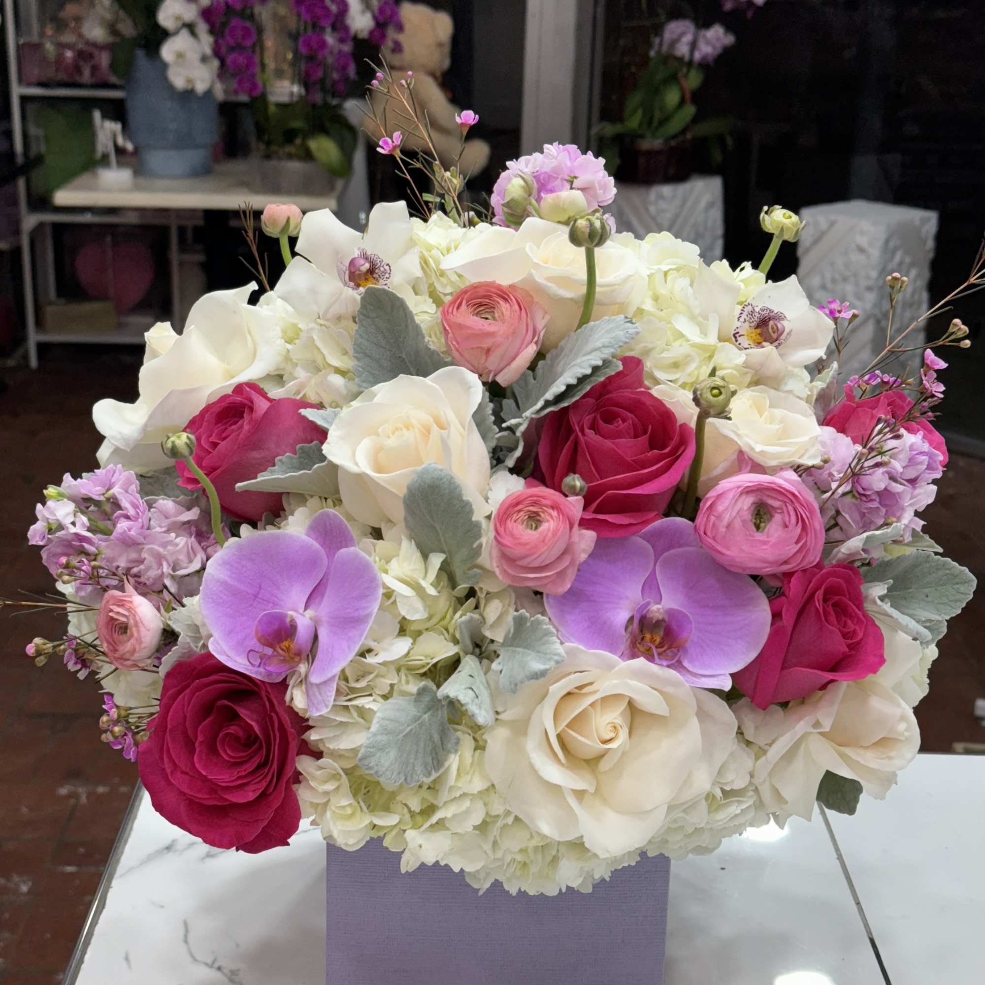 Pink and white rose bouquet with orchids in a lavender box