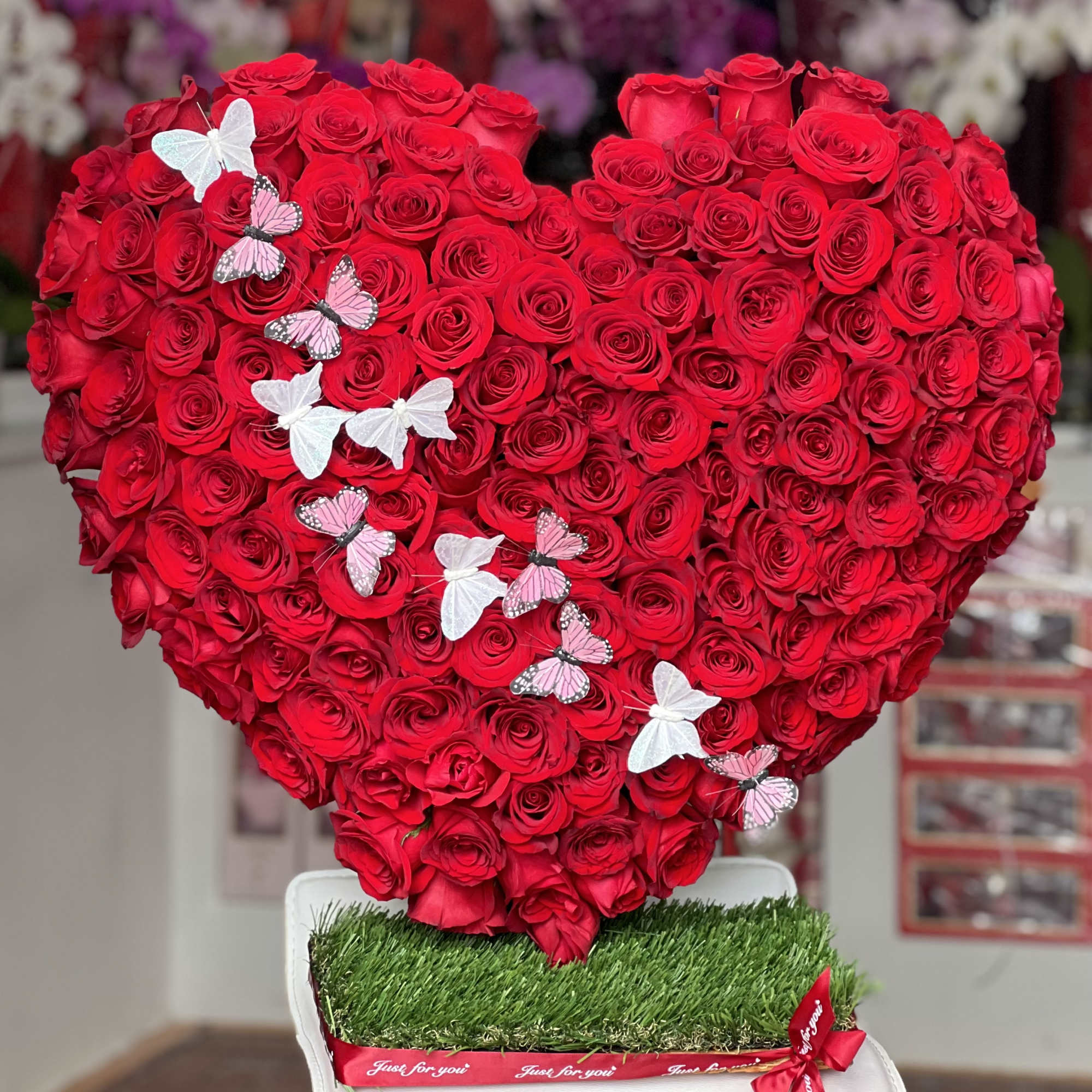 Heart-shaped arrangement of red roses with butterfly decorations on a white base, photo 2 of 4