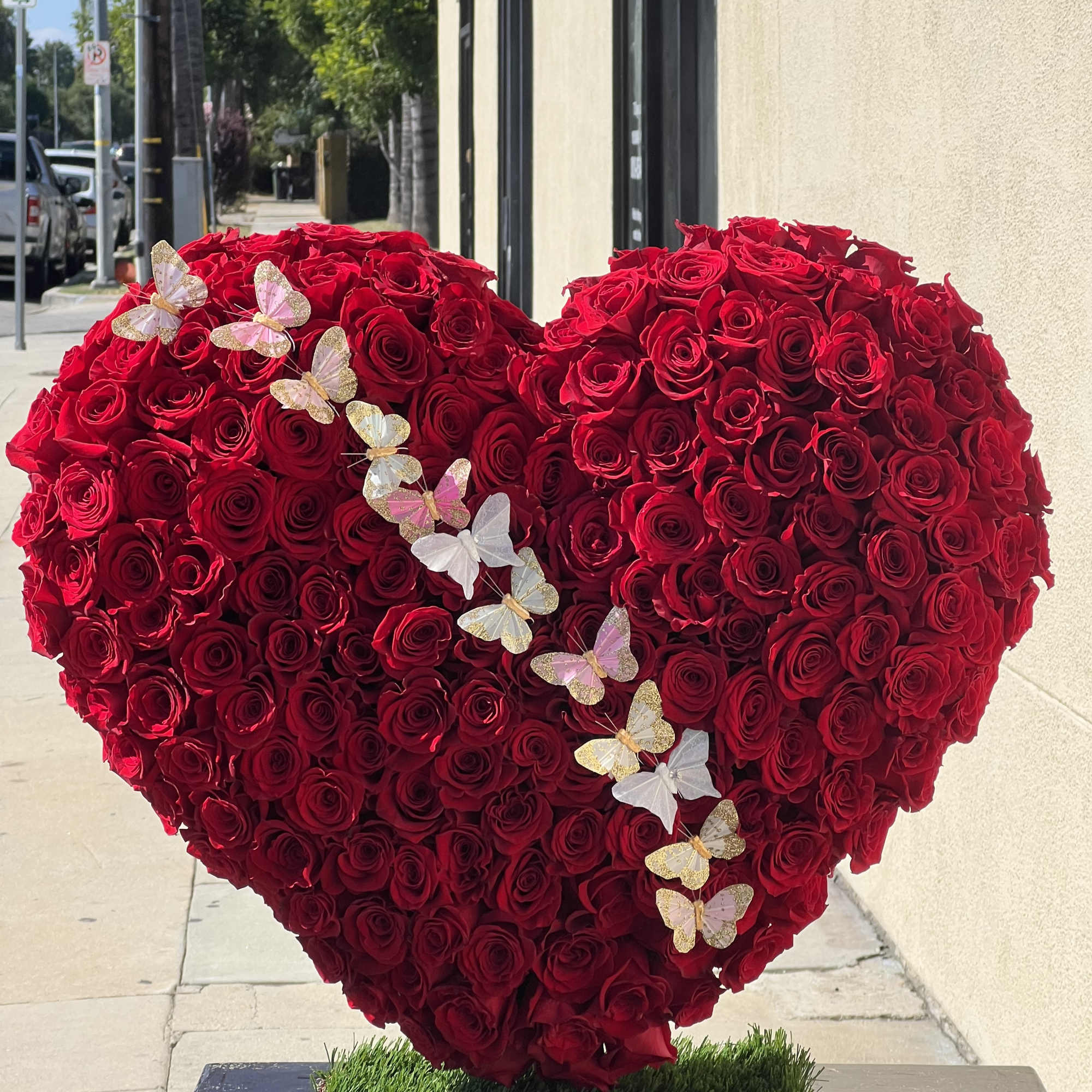 Heart-shaped arrangement of red roses with butterfly decorations