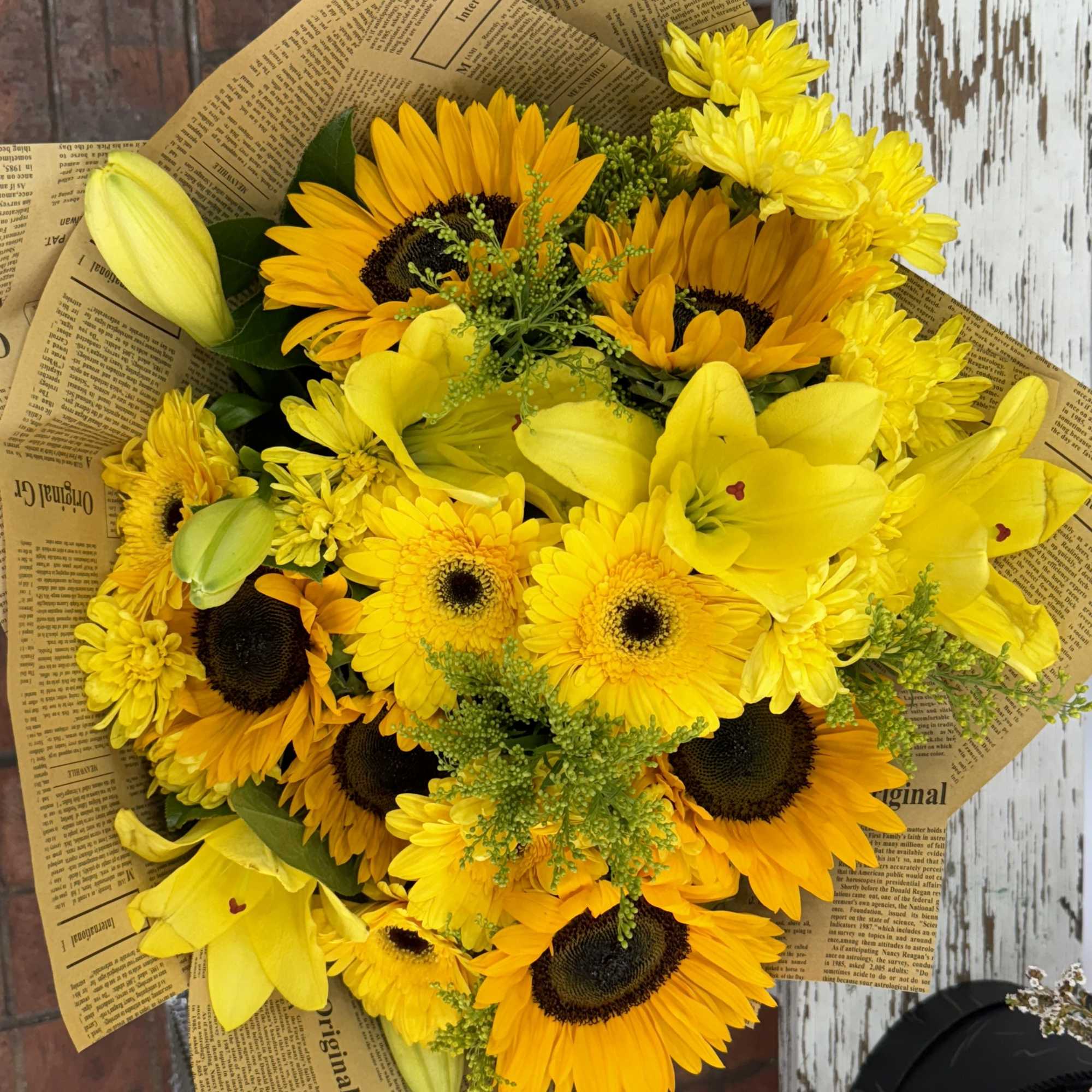 Bouquet of yellow sunflowers and lilies wrapped in newspaper-style paper, photo 2 of 2