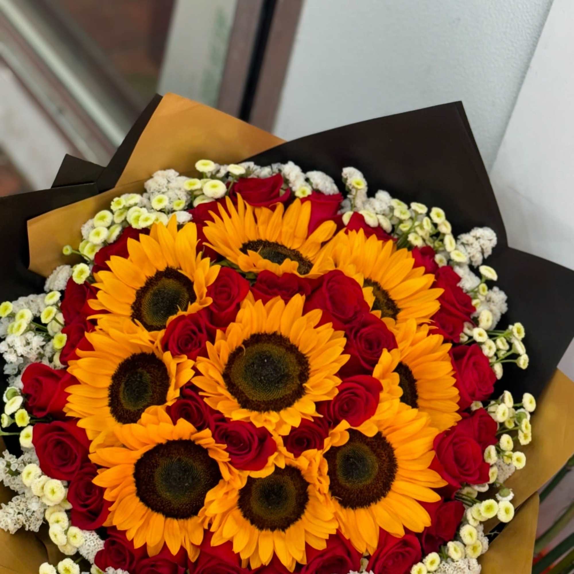 Bouquet of sunflowers and red roses with small white filler flowers