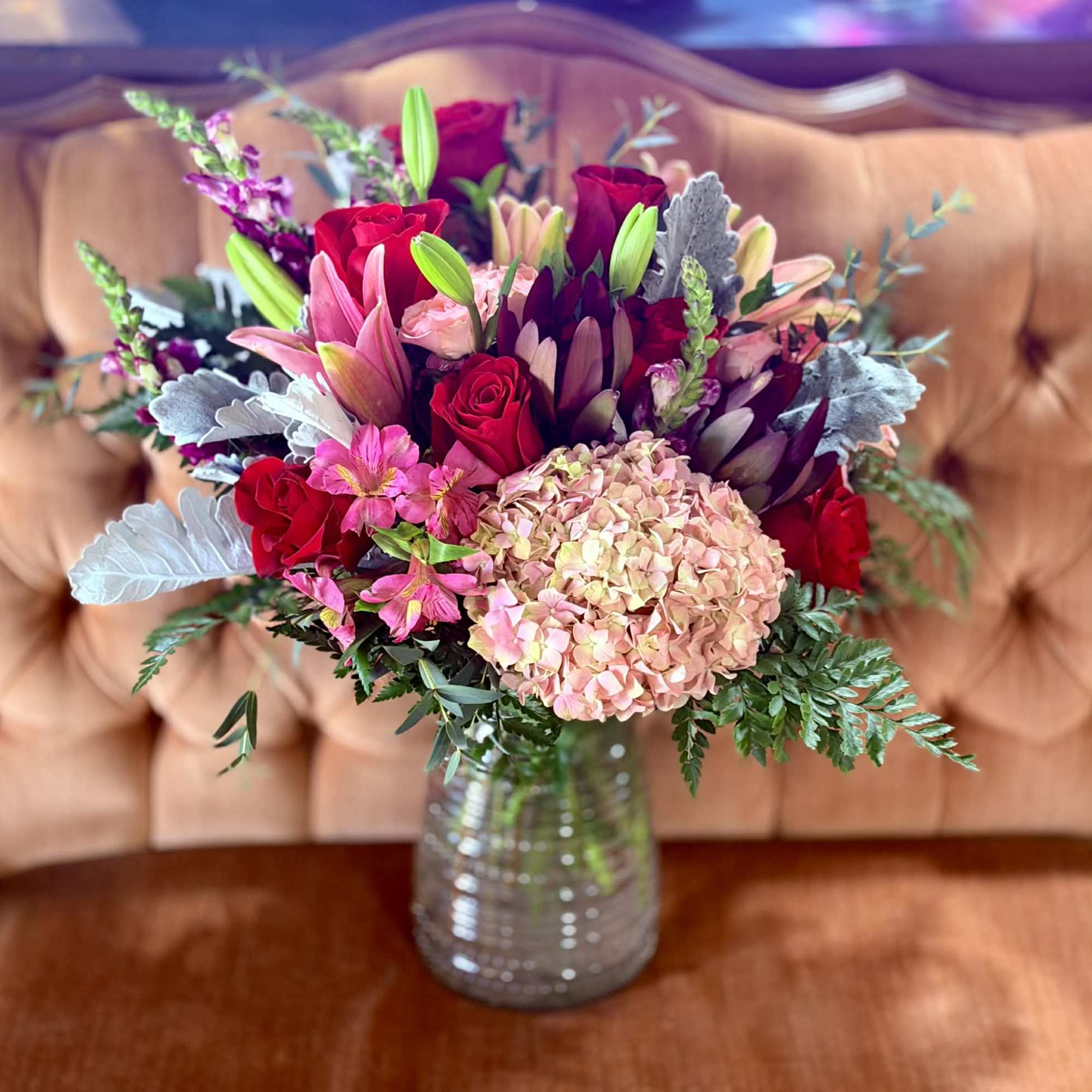 Bouquet of red roses, pink lilies, and hydrangea in a glass vase