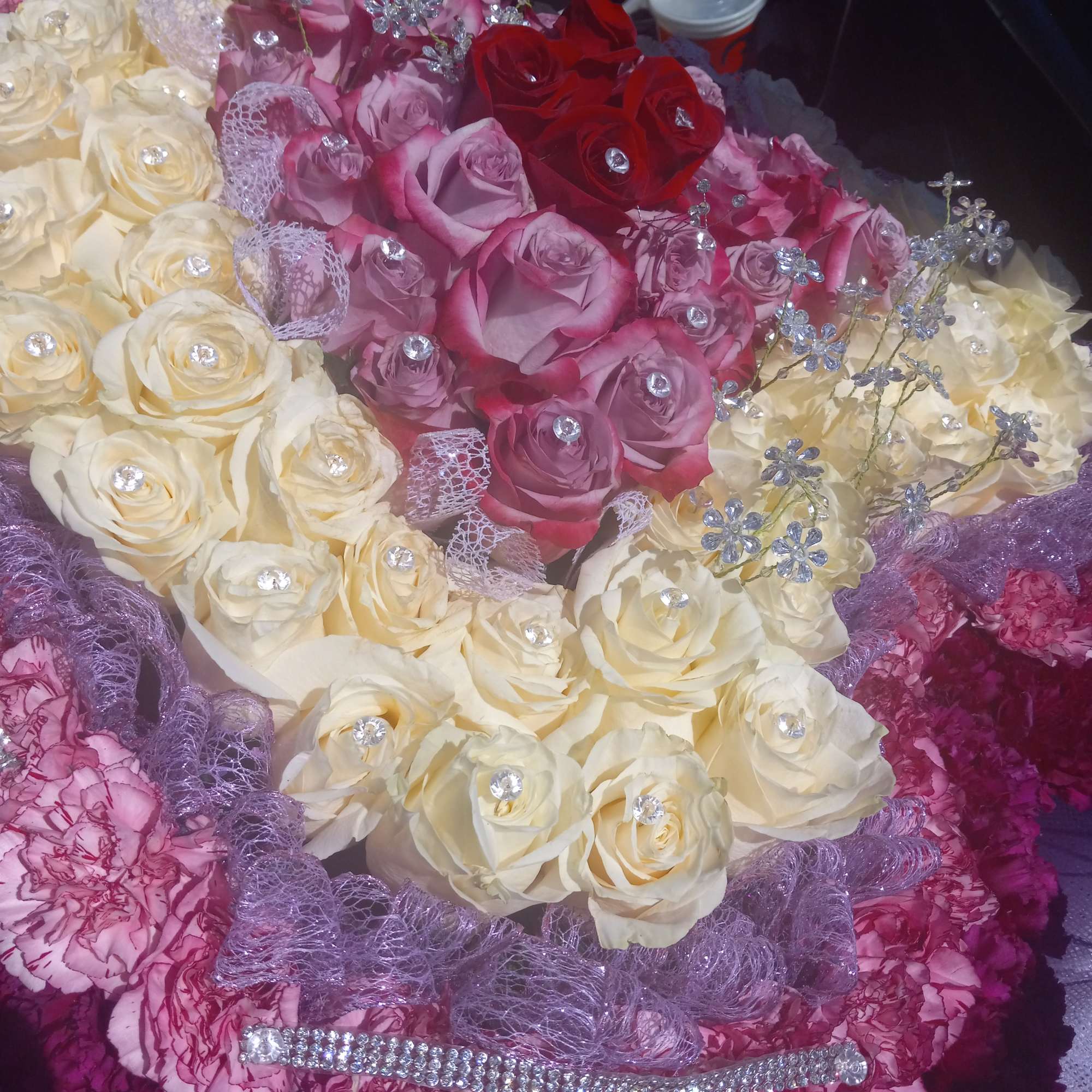 Bouquet of cream, pink, and red roses with jeweled accents