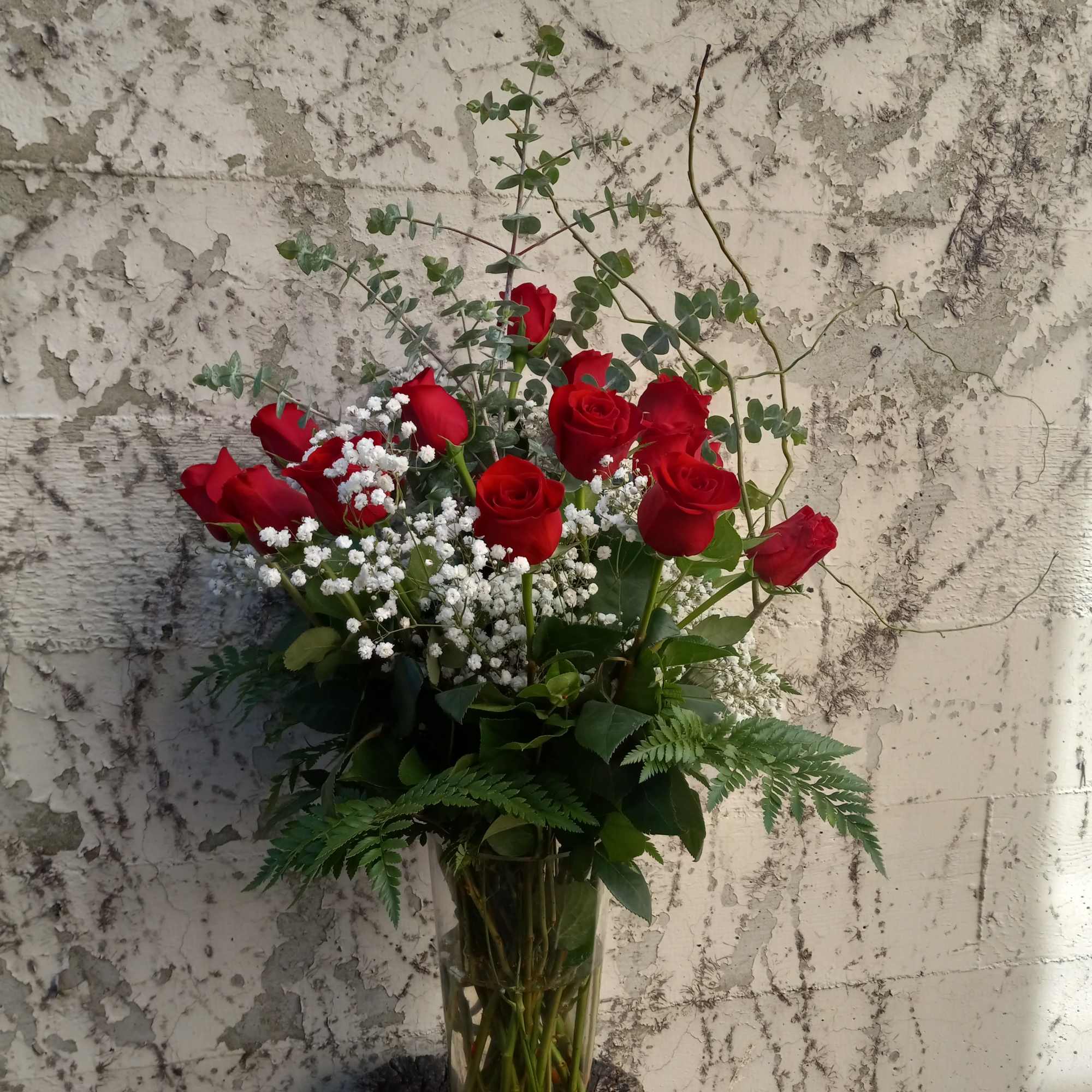 This is a vase of a dozen red roses elegantly arranged in