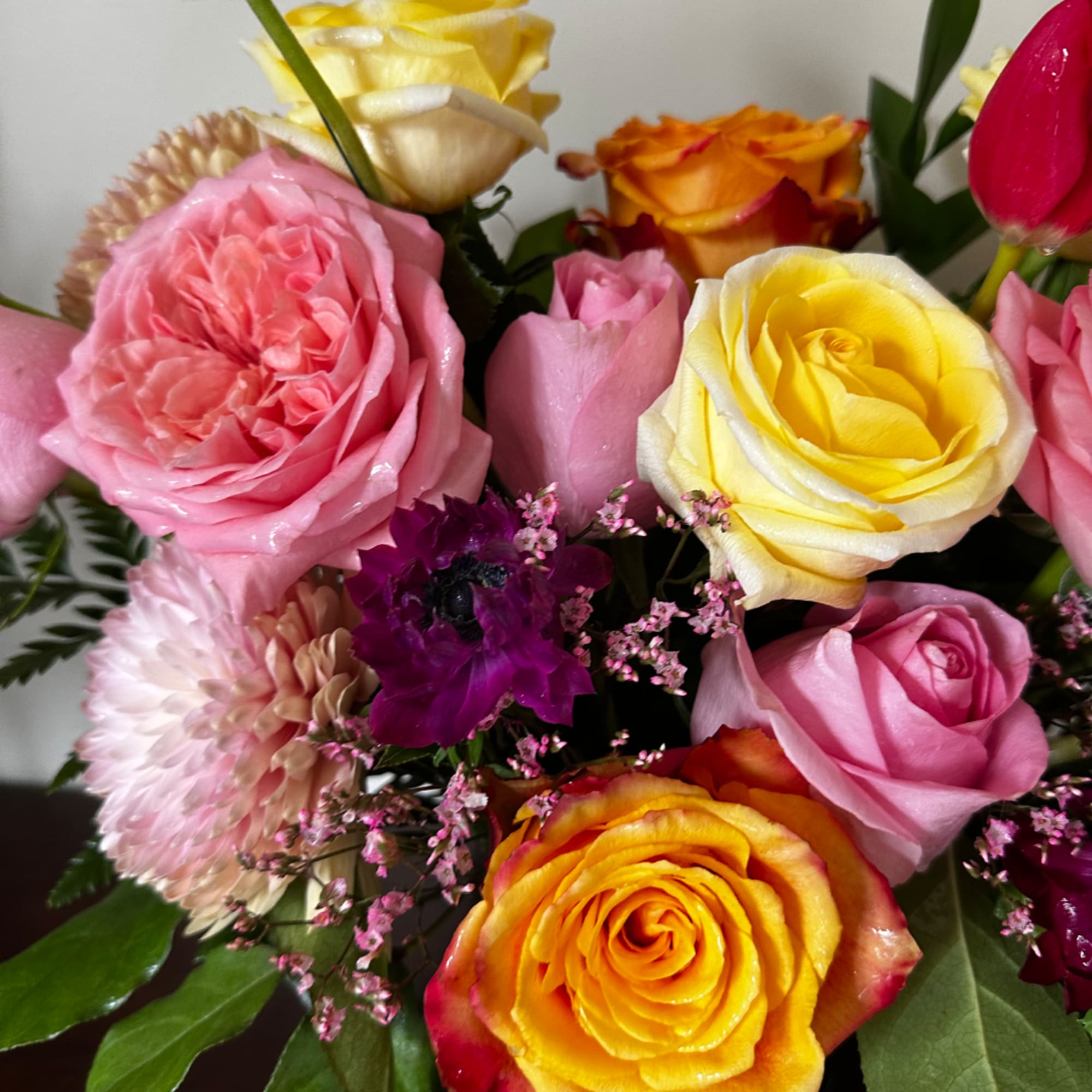 Mixed bouquet of pink, yellow, and orange roses with small accent flowers, photo 4 of 7