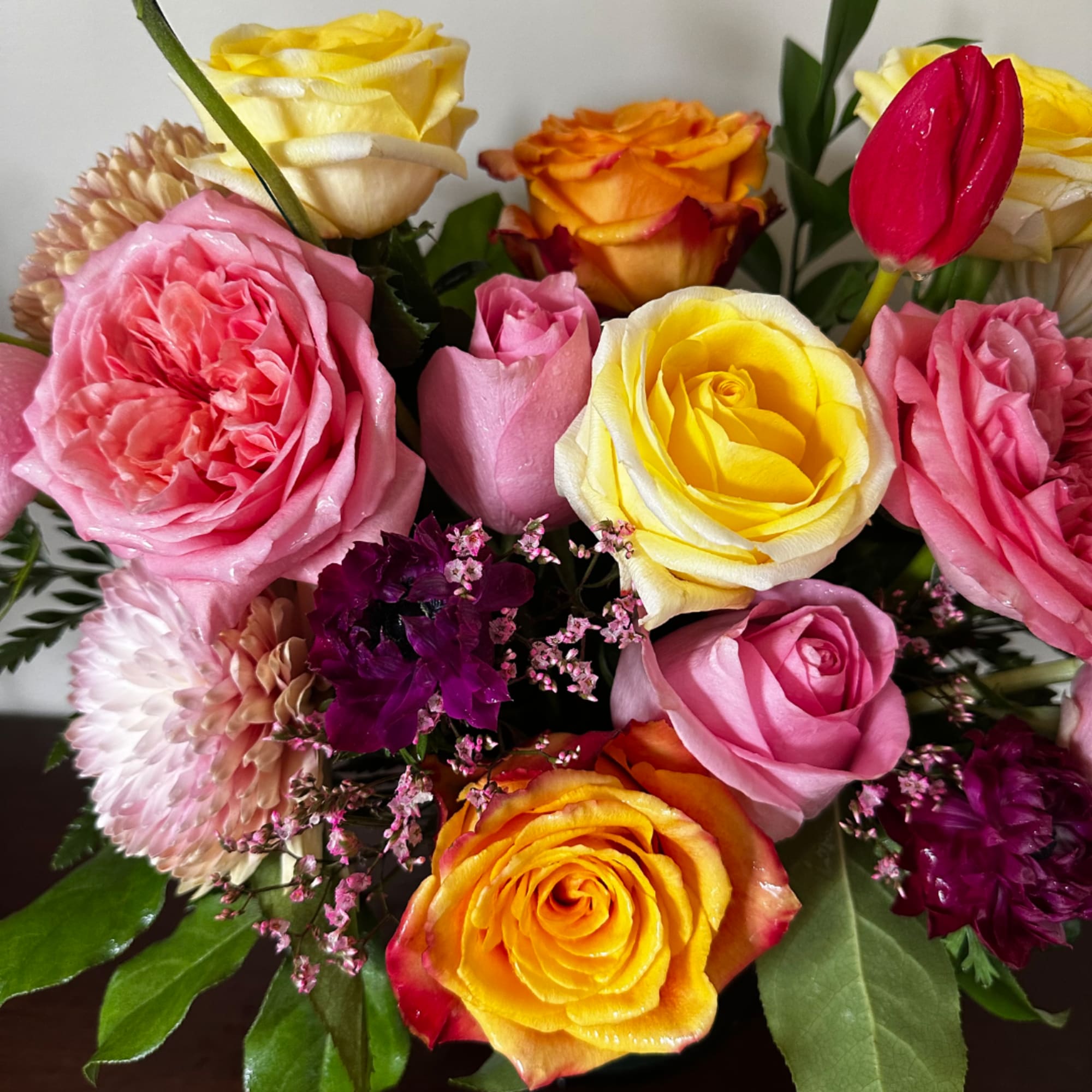 Mixed bouquet of pink, yellow, and orange roses with small accent flowers, photo 5 of 7