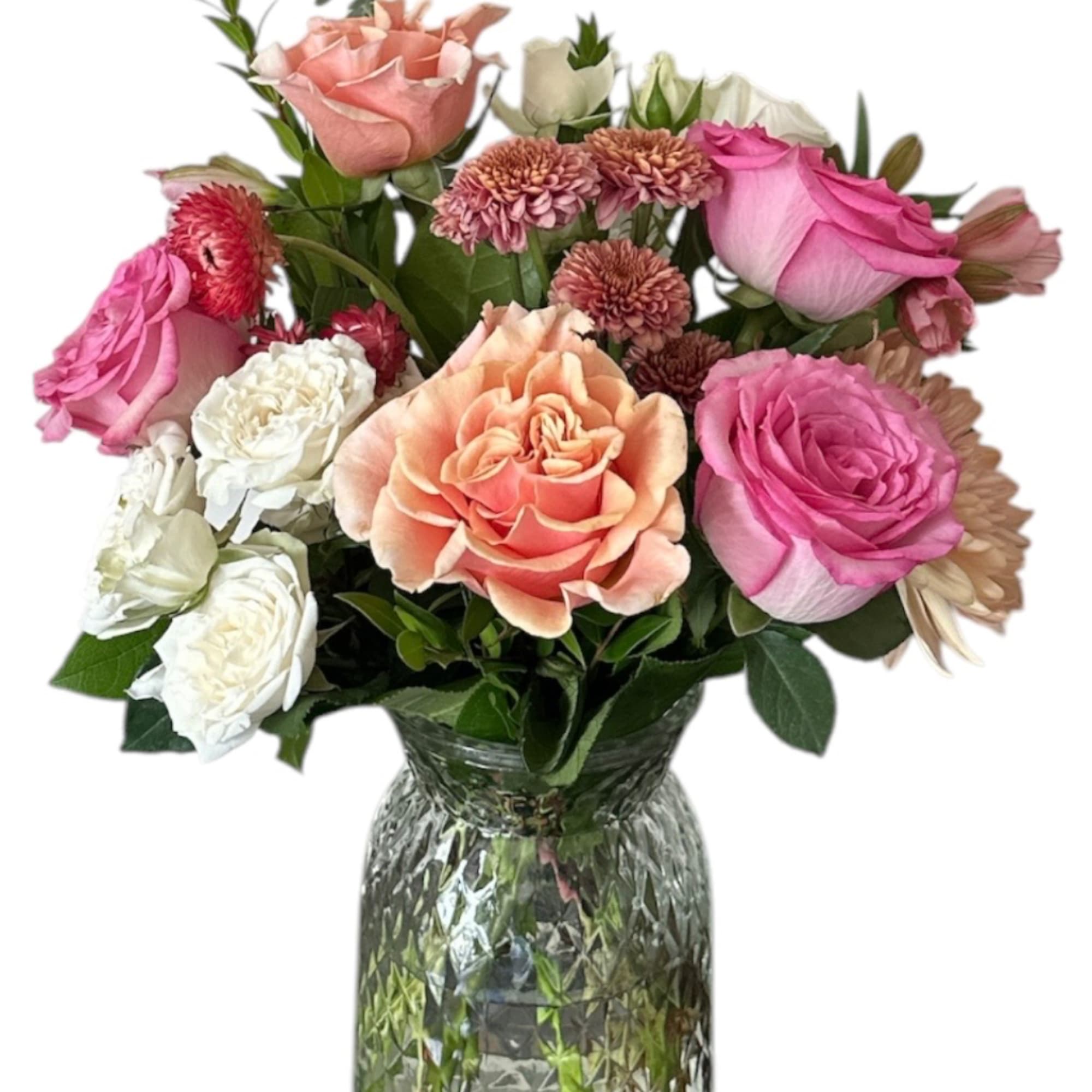 Mixed pink, peach, and white flowers in a clear glass vase