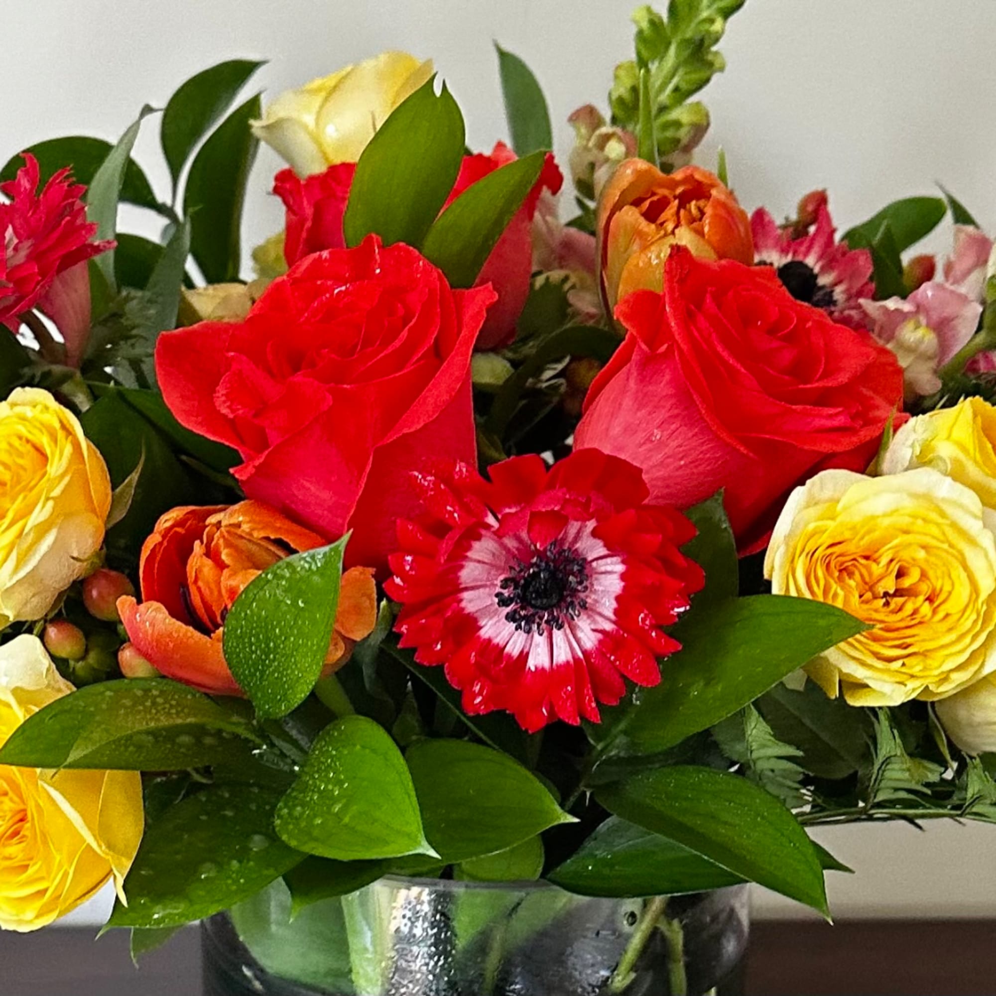Mixed bouquet of red, yellow, and orange flowers in a glass vase
