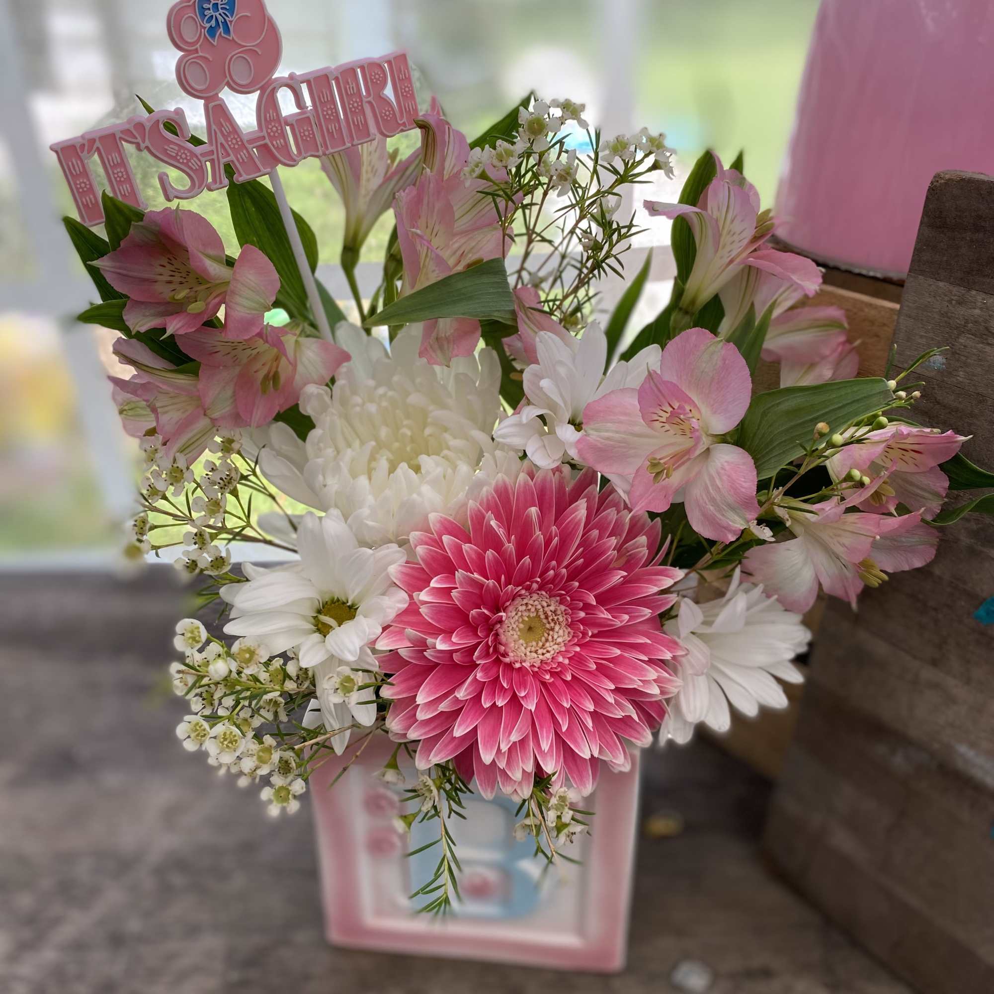 Pink and white flower arrangement in a baby-themed vase with an 'It's a Girl' pick
