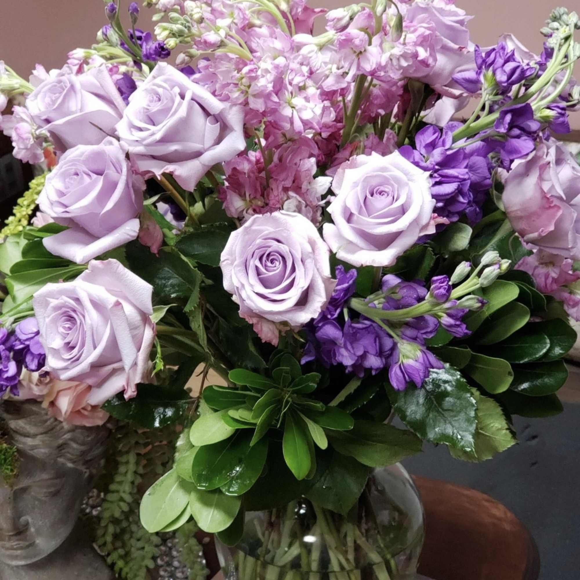 Lavender roses and purple flowers in a glass vase