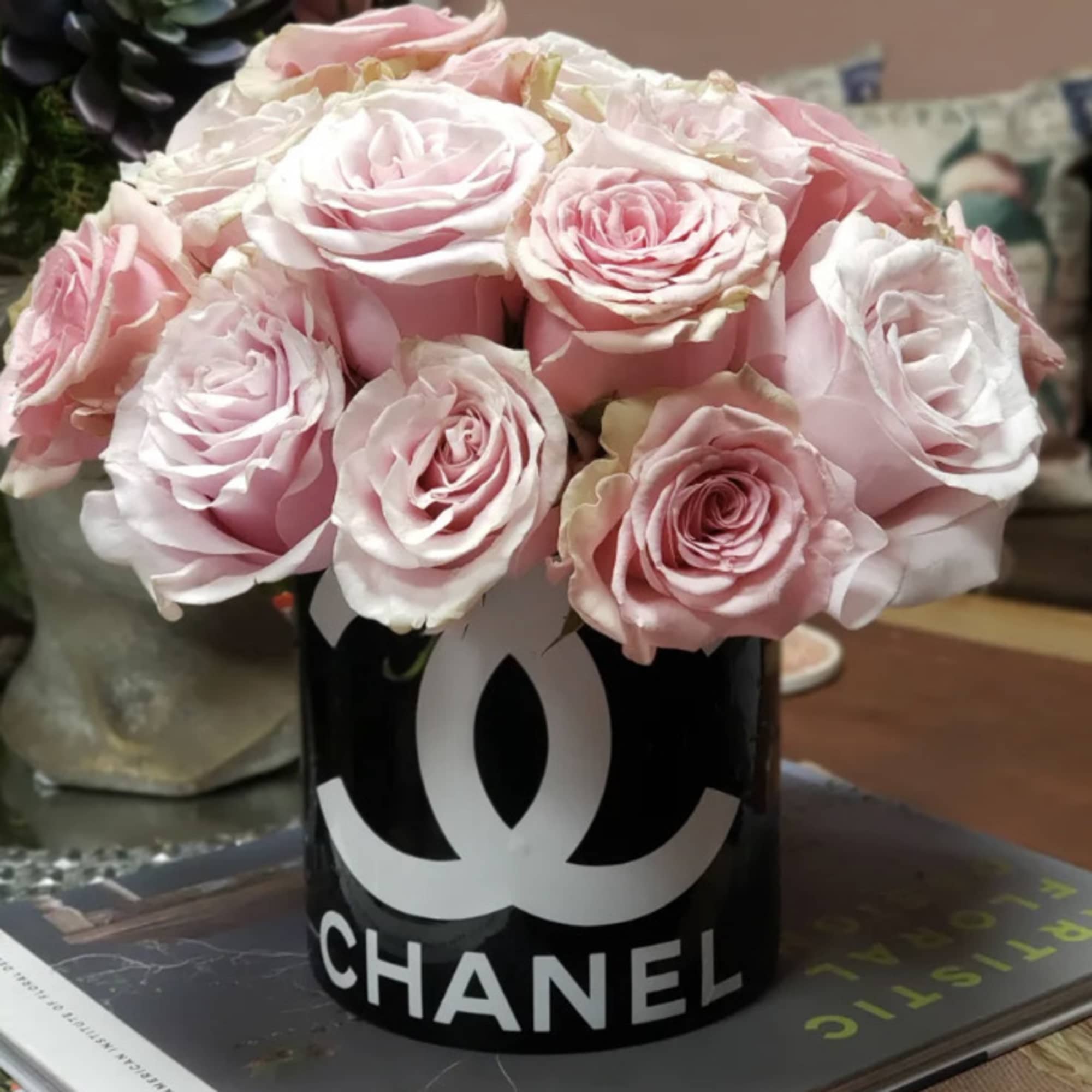 Pink roses arranged in a black Chanel container