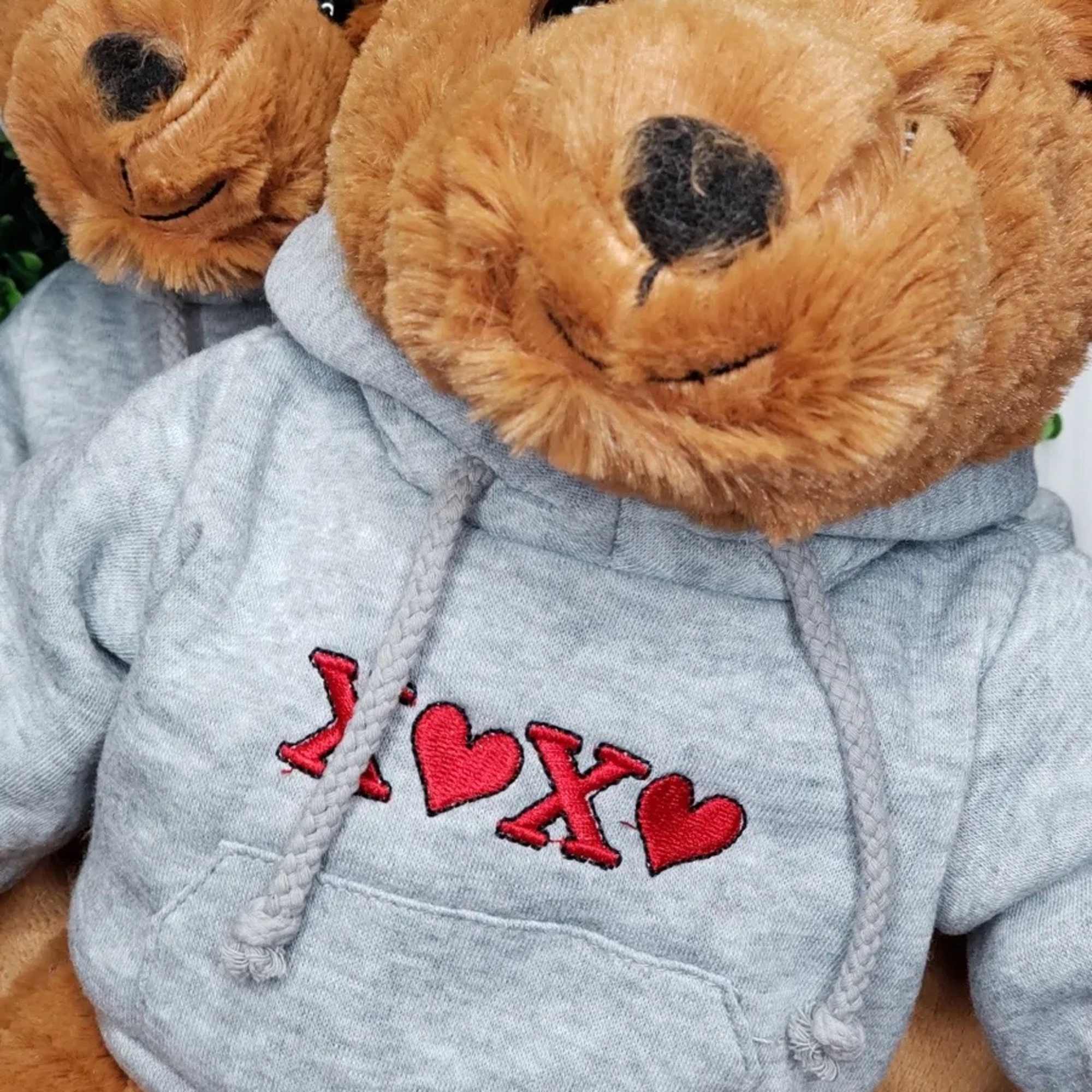 Two teddy bears in gray hoodies with red heart embroidery