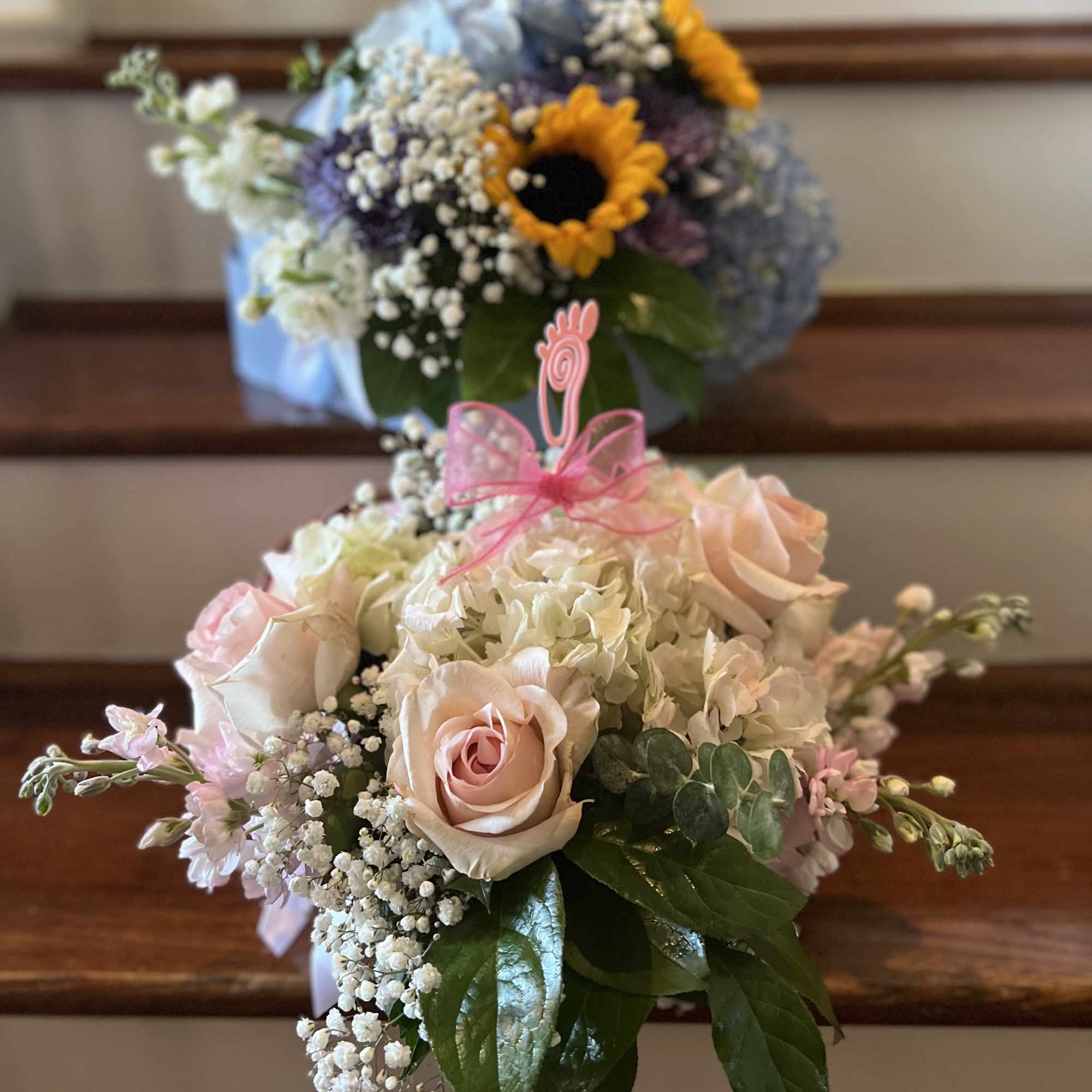 Two pastel floral bouquets on stairs, one with roses and hydrangea