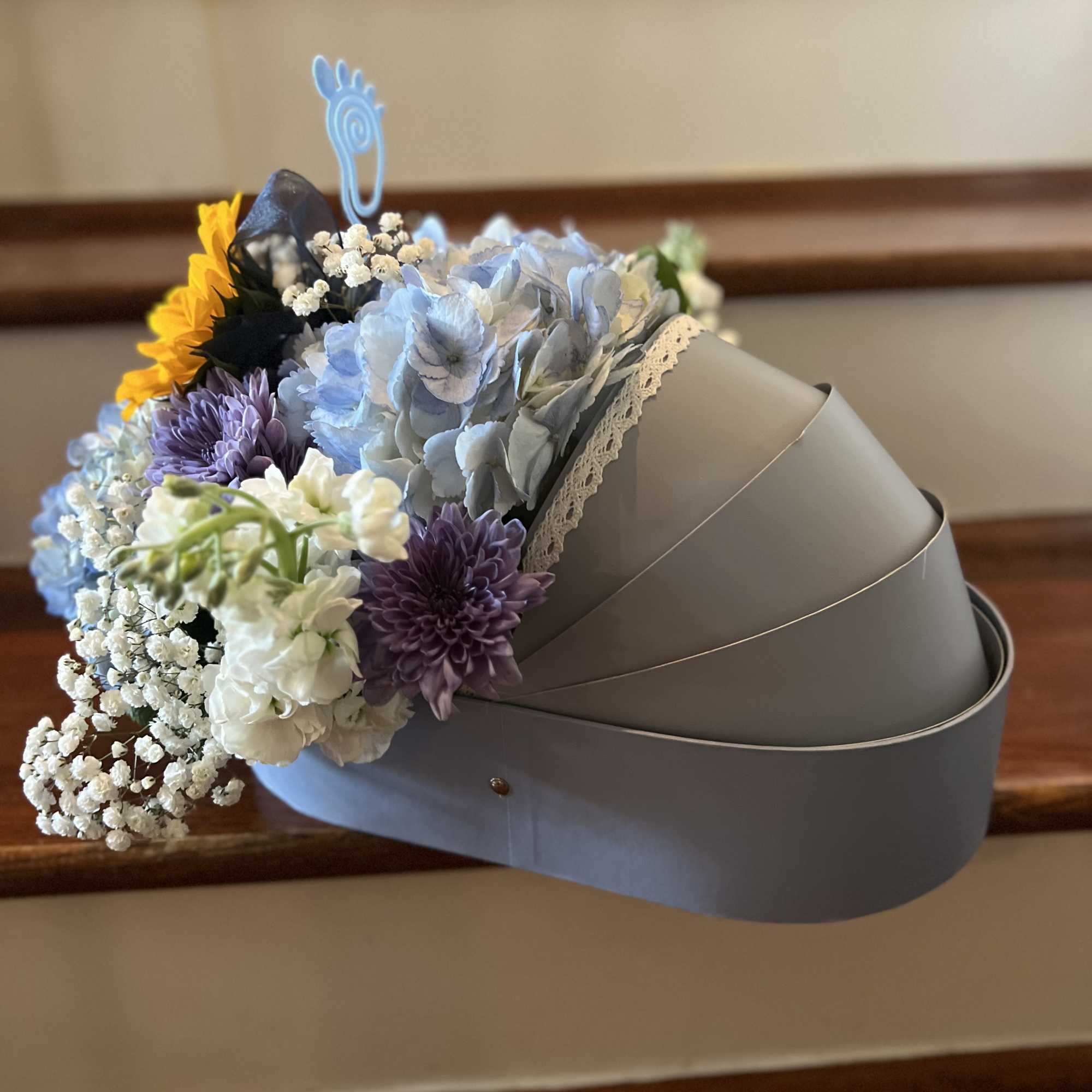 Bouquet of blue, purple, white, and yellow flowers in a gray hatbox
