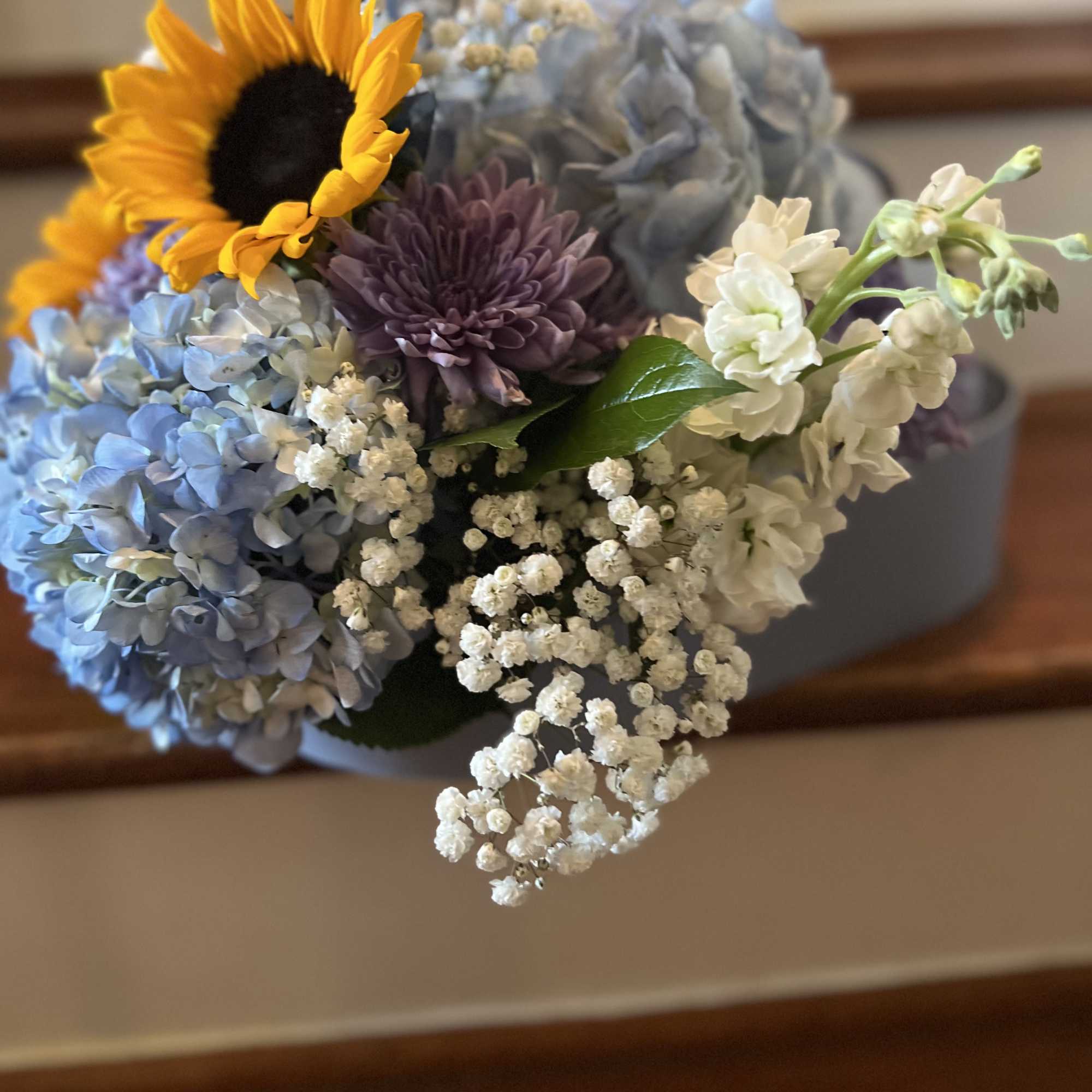 Bouquet with a sunflower, blue hydrangeas, and white filler flowers