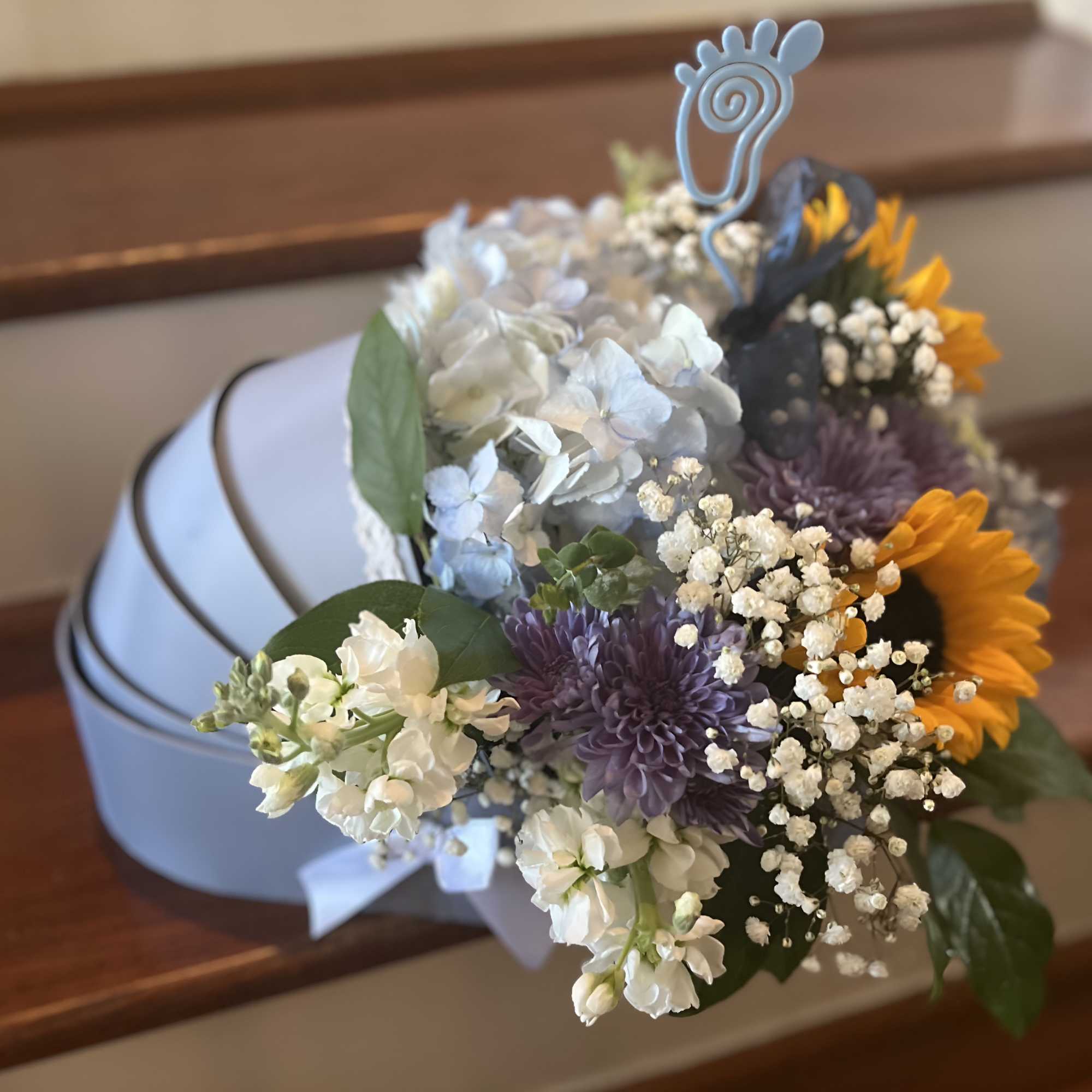 Bouquet of white, purple, and yellow flowers in a light blue hatbox