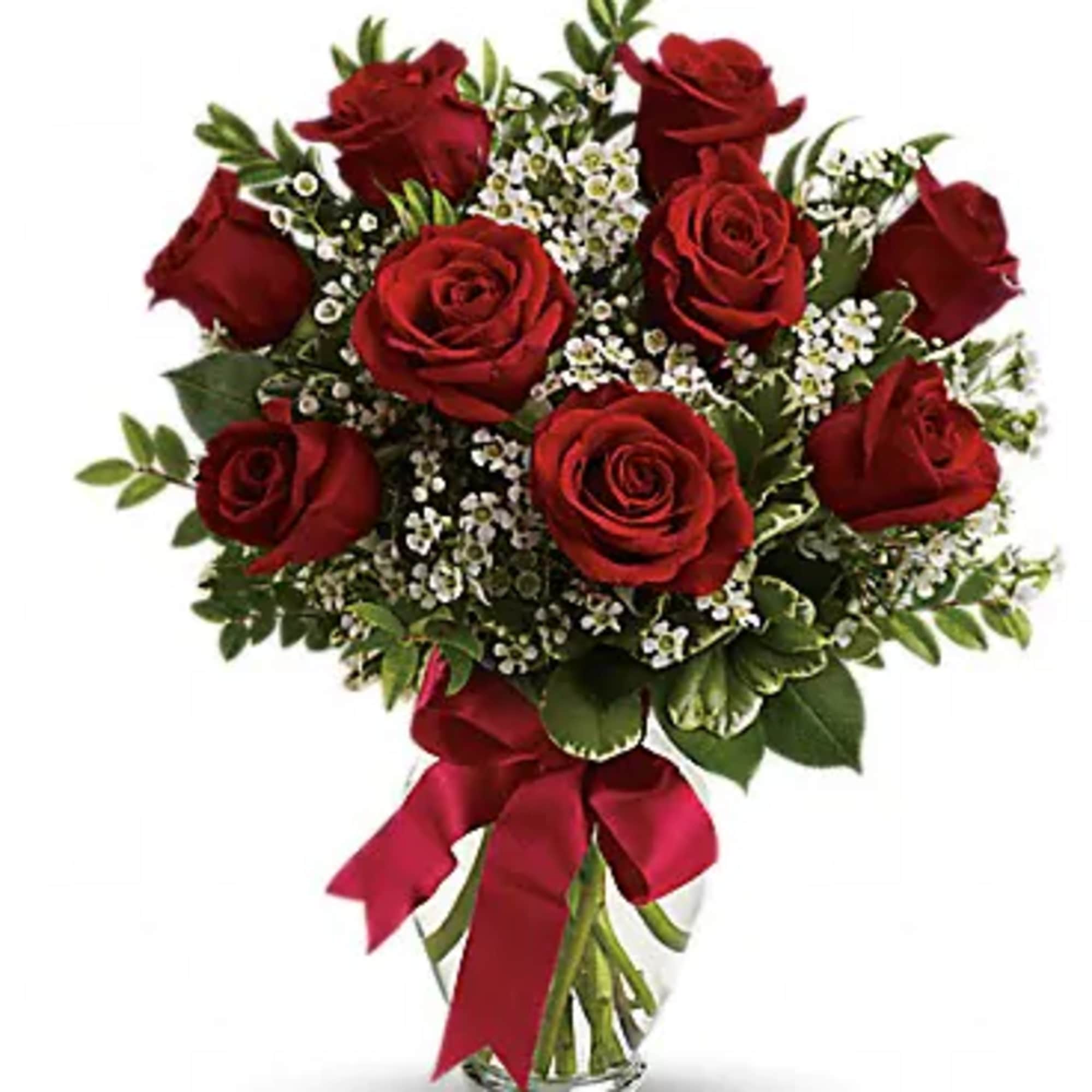 Bouquet of red roses with white filler flowers in a glass vase tied with a red ribbon