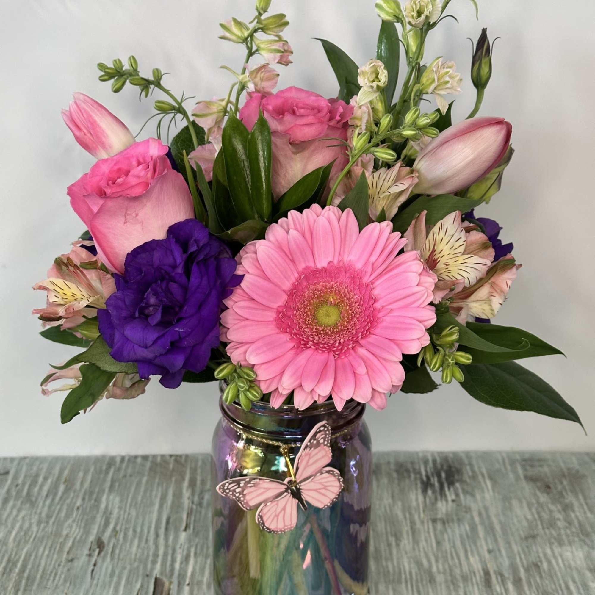 Pink and purple mixed bouquet in a iridescent vase with butterfly decoration
