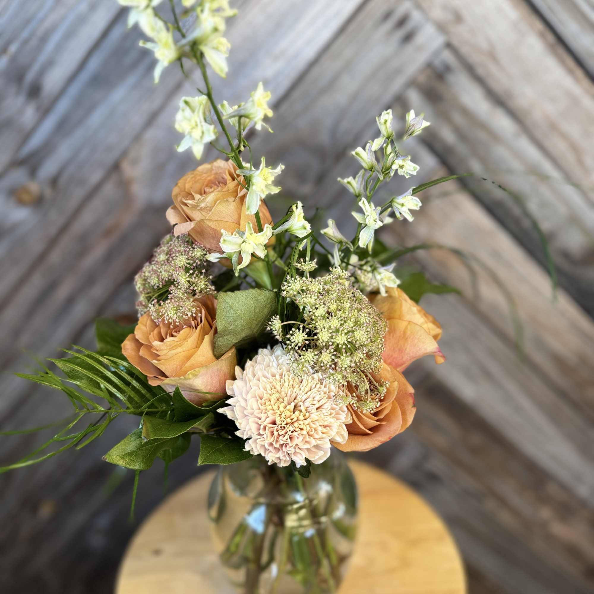 Peach roses and a pale chrysanthemum in a glass vase