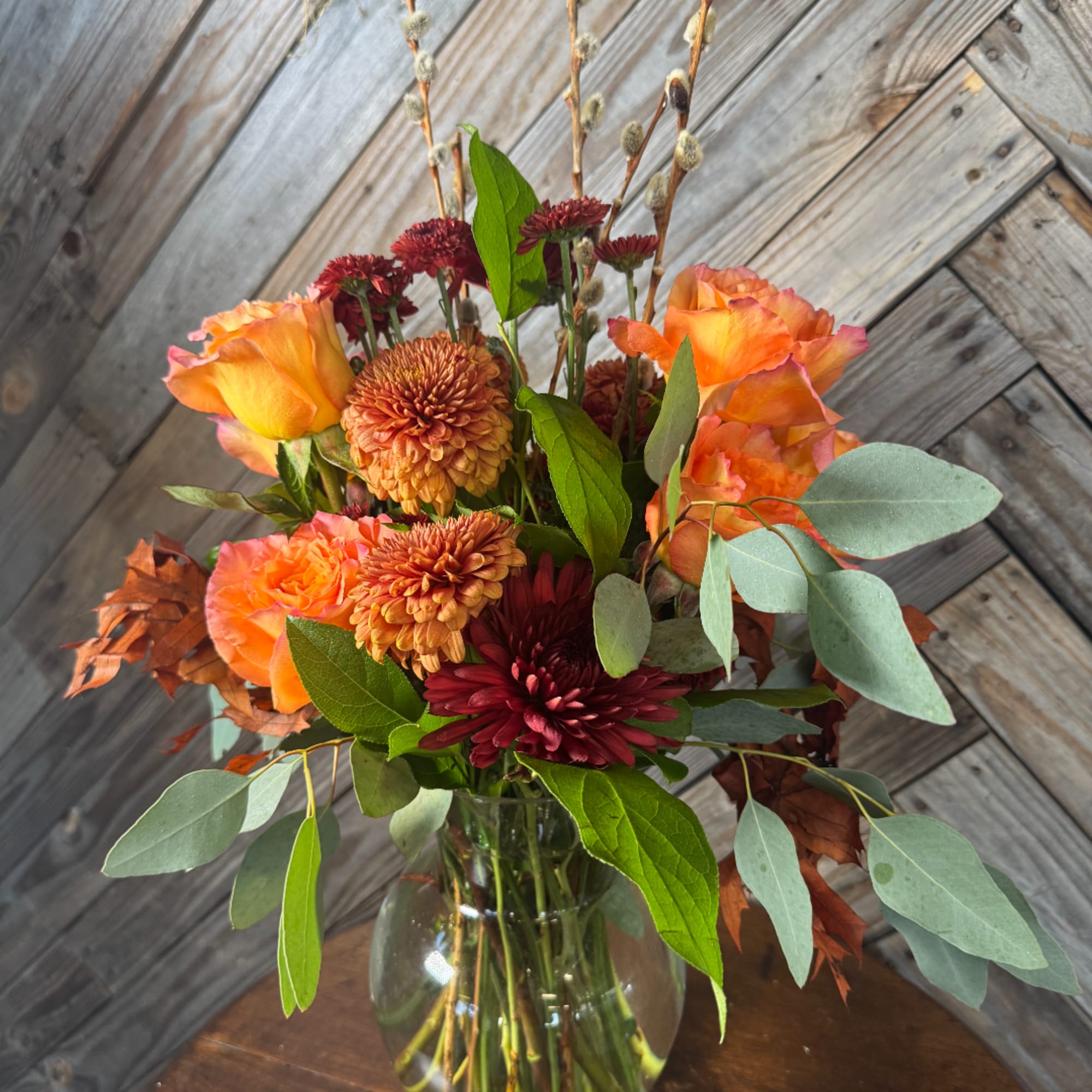 Orange roses and burgundy chrysanthemums in a glass vase