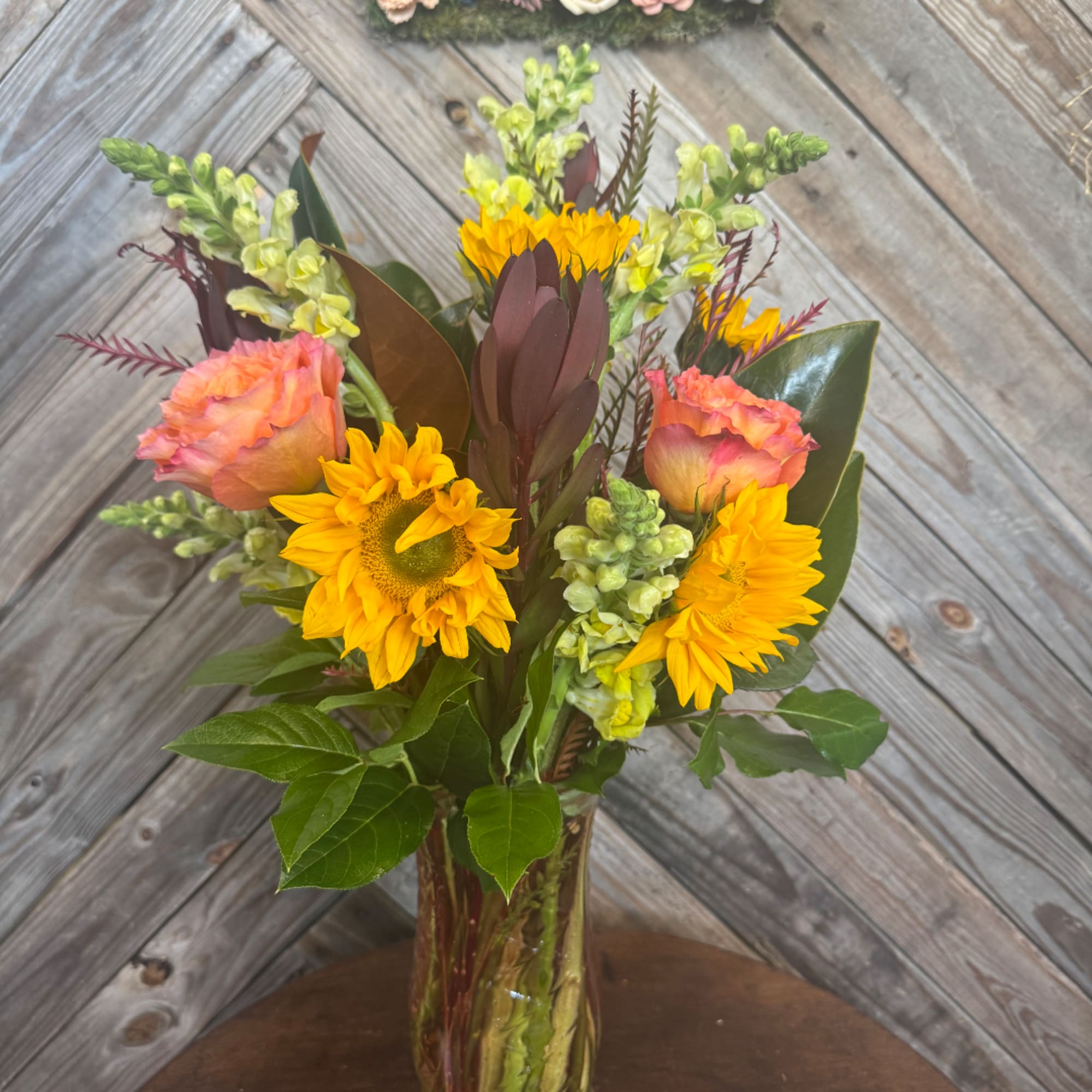 Bouquet of sunflowers and peach roses in a glass vase