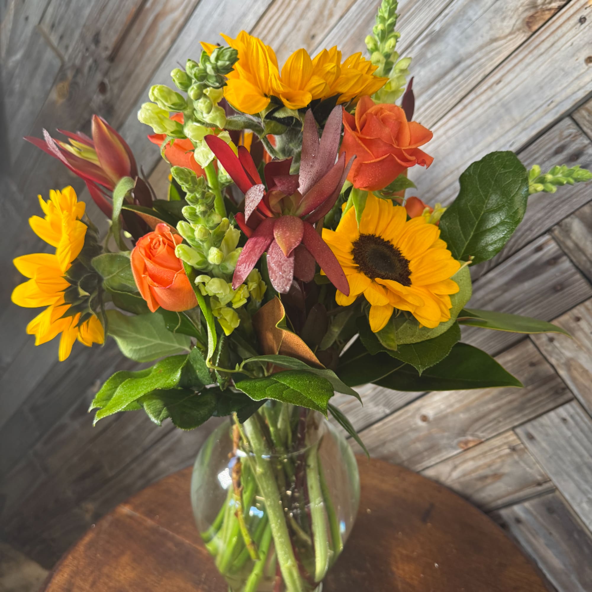 Sunflowers and orange roses in a clear glass vase