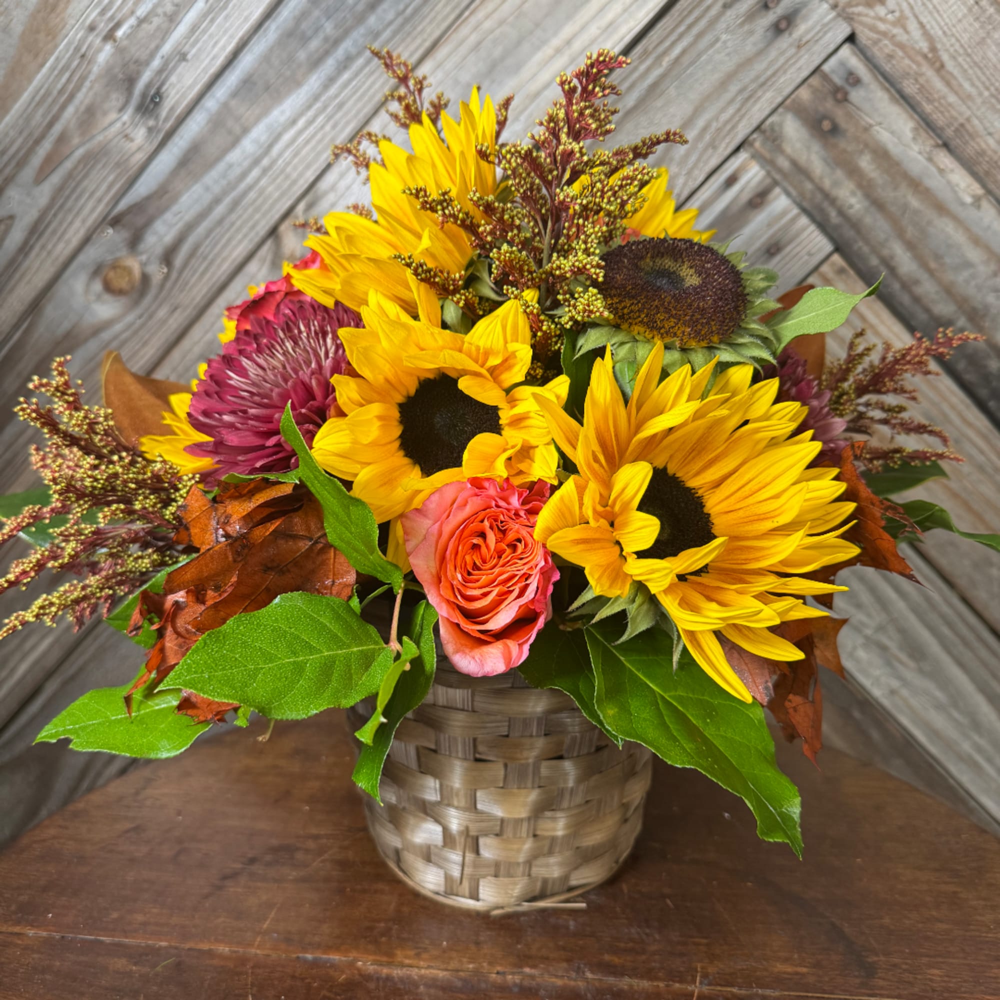 Sunflower and rose arrangement in a woven basket