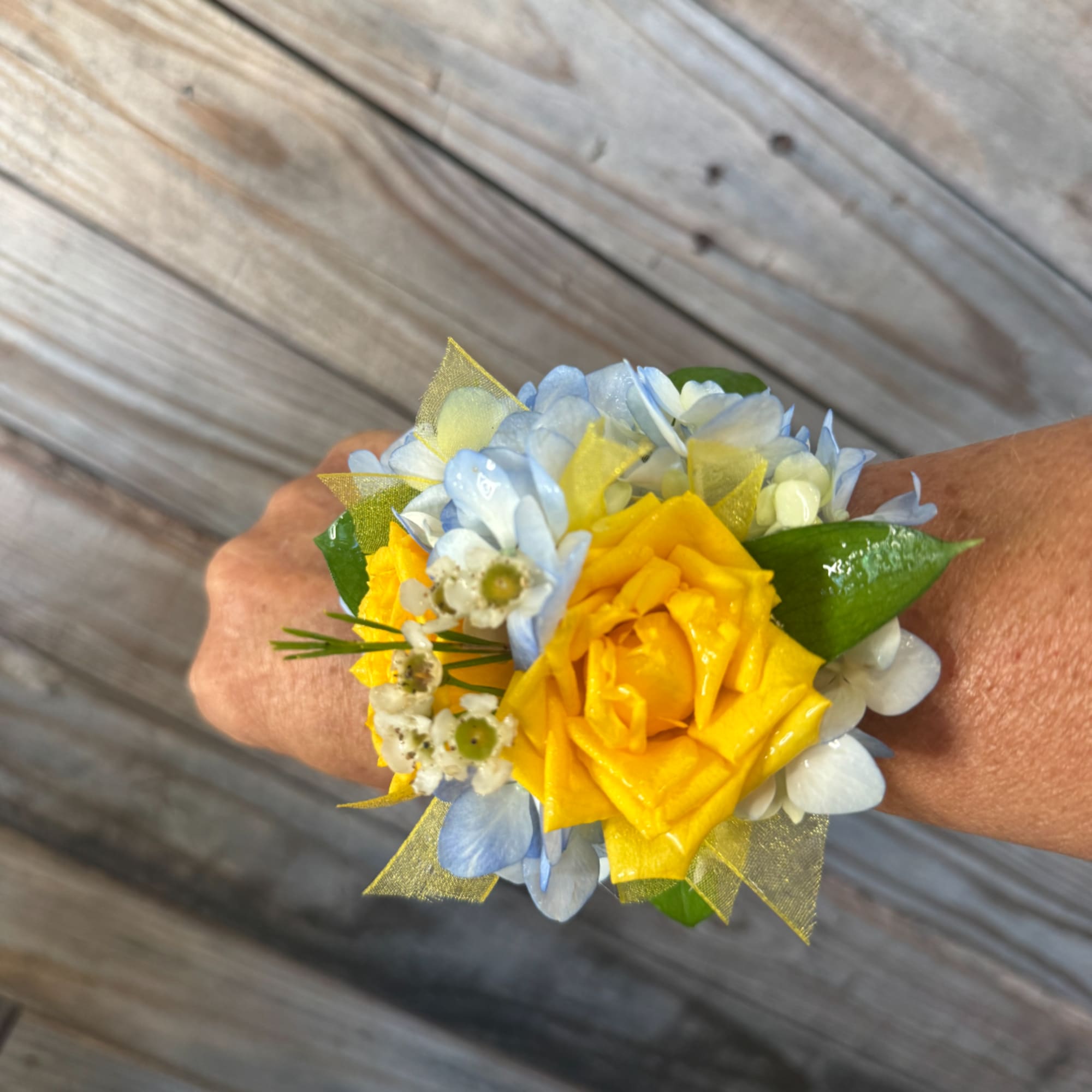 Yellow rose wrist corsage with pale blue flowers and ribbon accents
