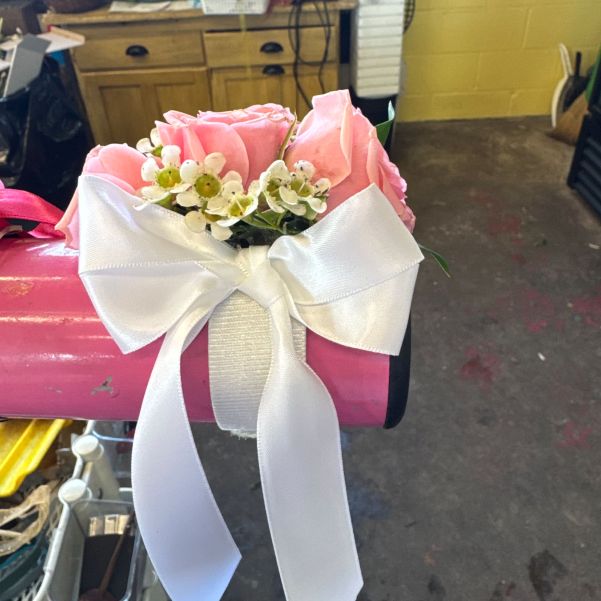 Pink roses with small white filler flowers and a white bow