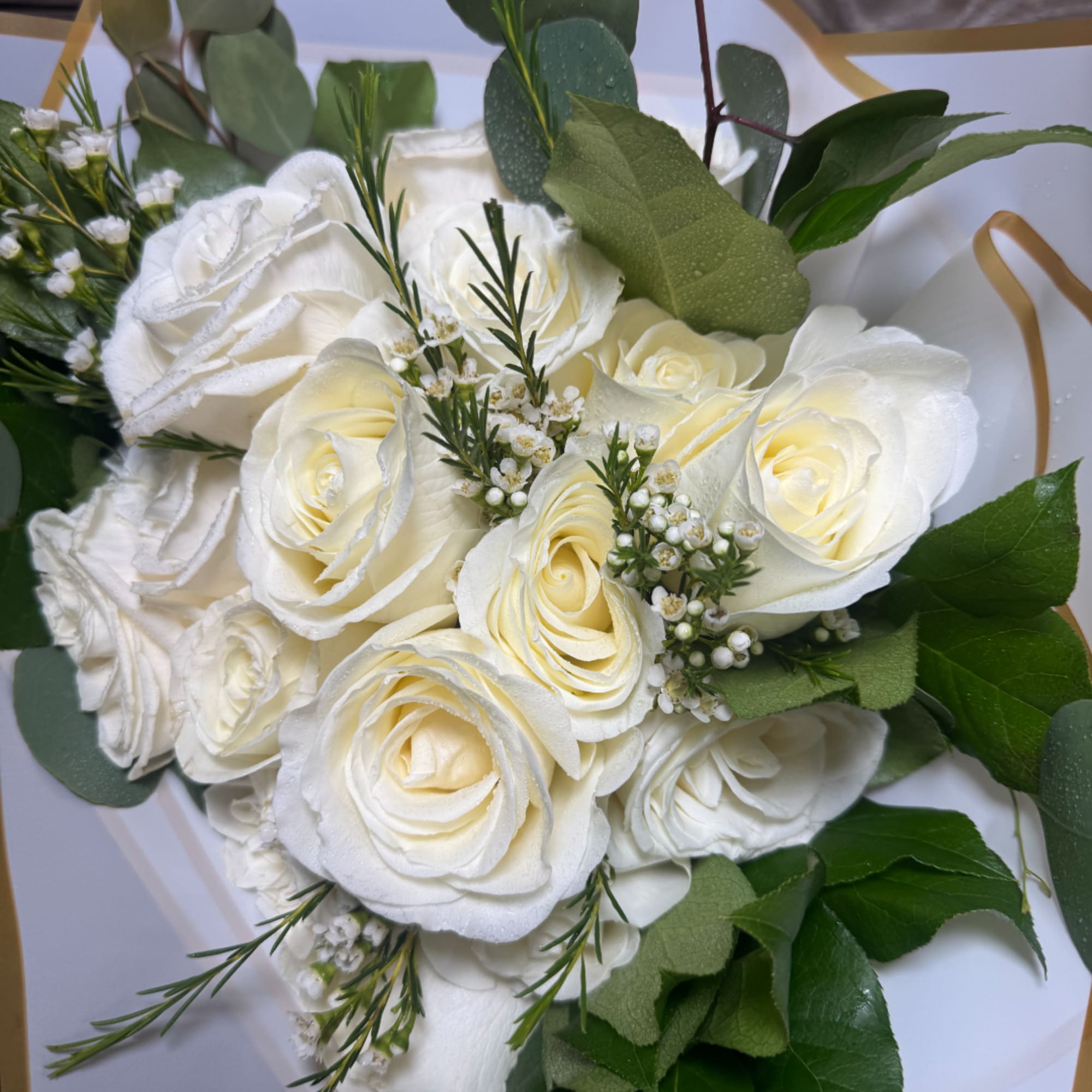 White rose bouquet with small white filler flowers and green leaves