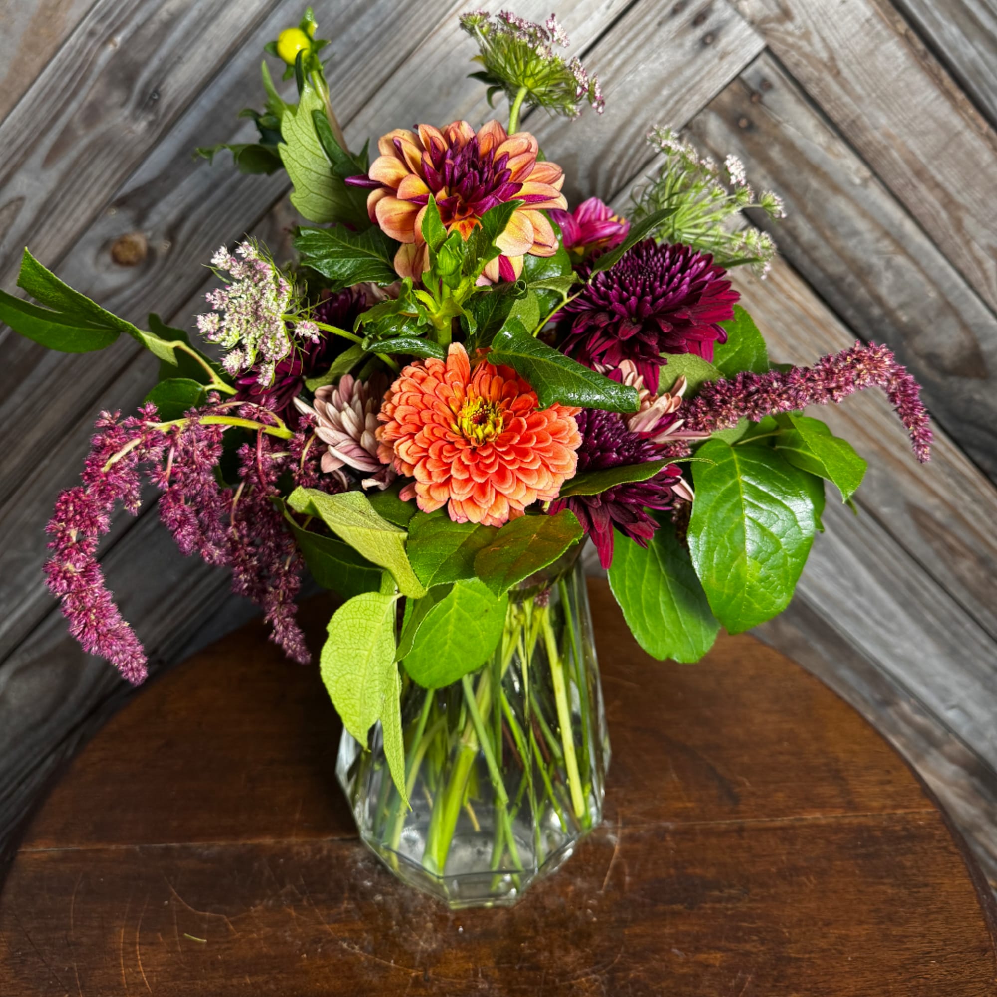 Mixed bouquet of orange and purple flowers in a clear glass vase