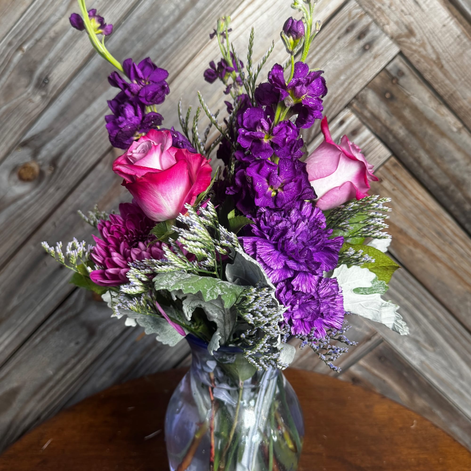 Purple and pink mixed bouquet in a clear glass vase