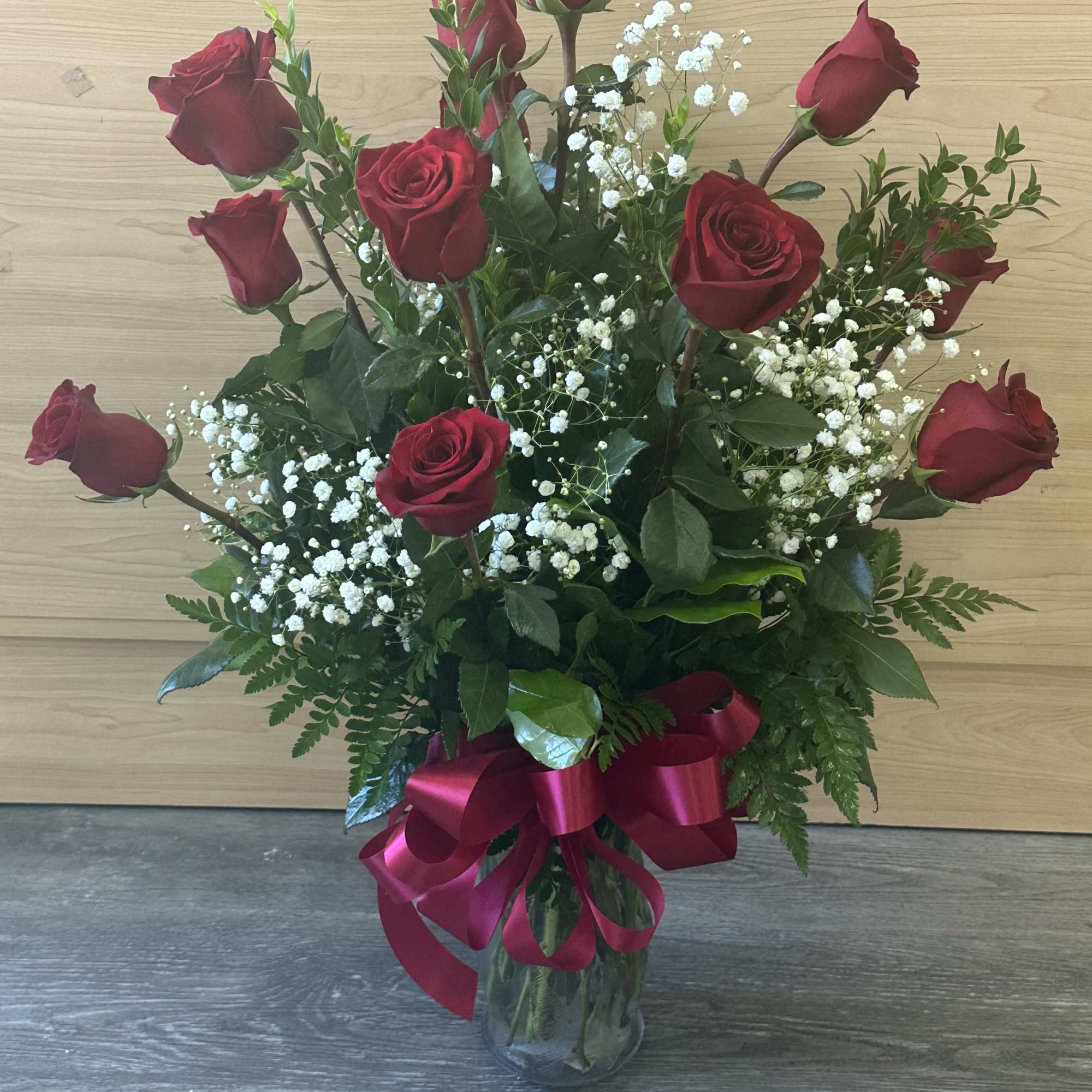 Tall bouquet of red roses with baby's breath in a glass vase