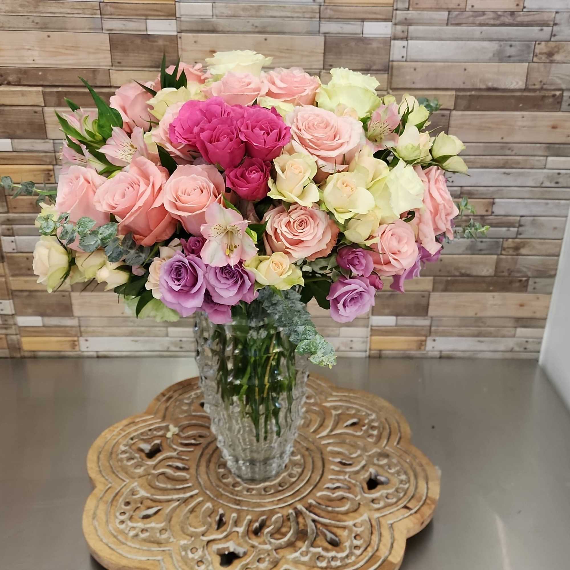 Mixed pink and lavender roses arranged in a clear glass vase