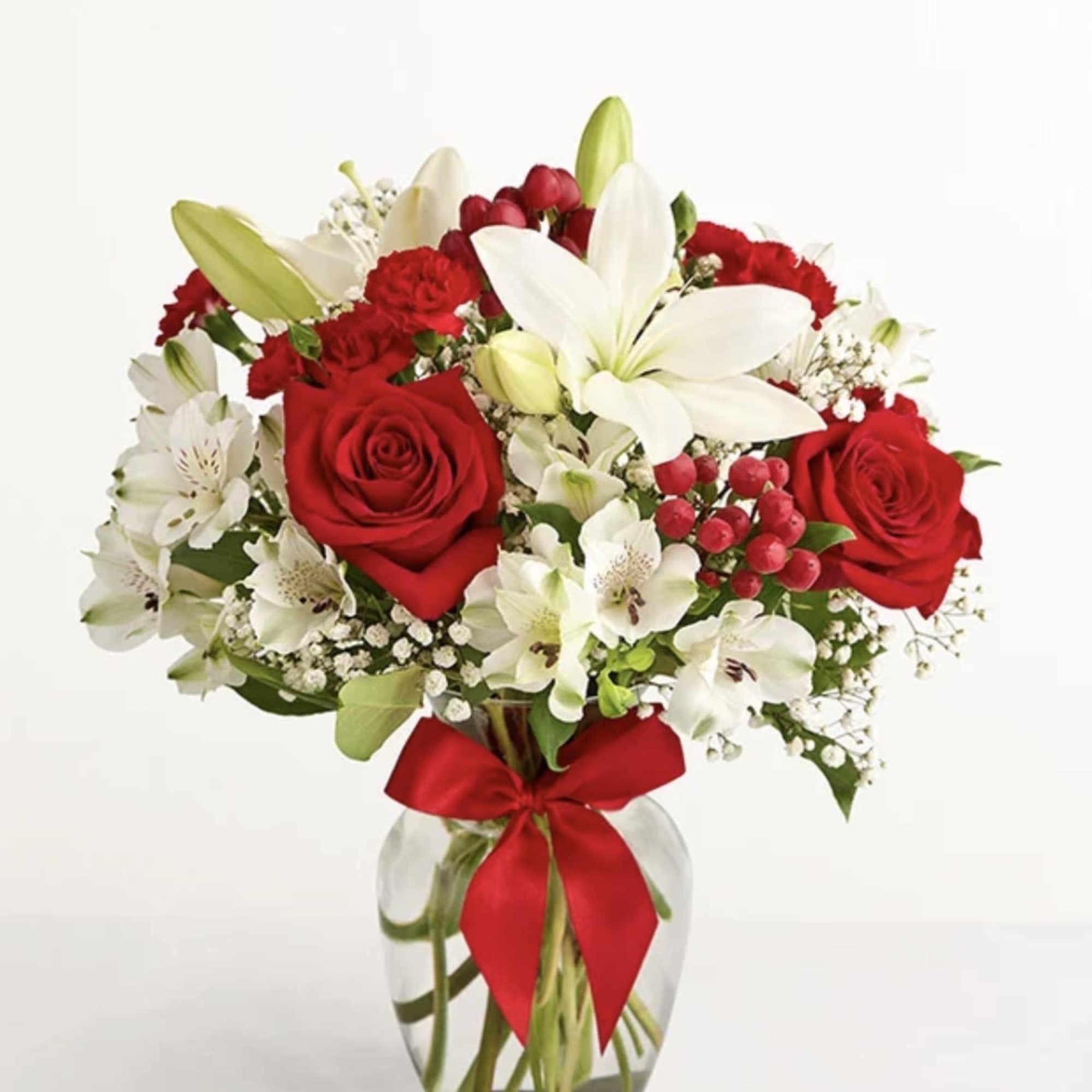 Red roses and white lilies in a glass vase with a red ribbon