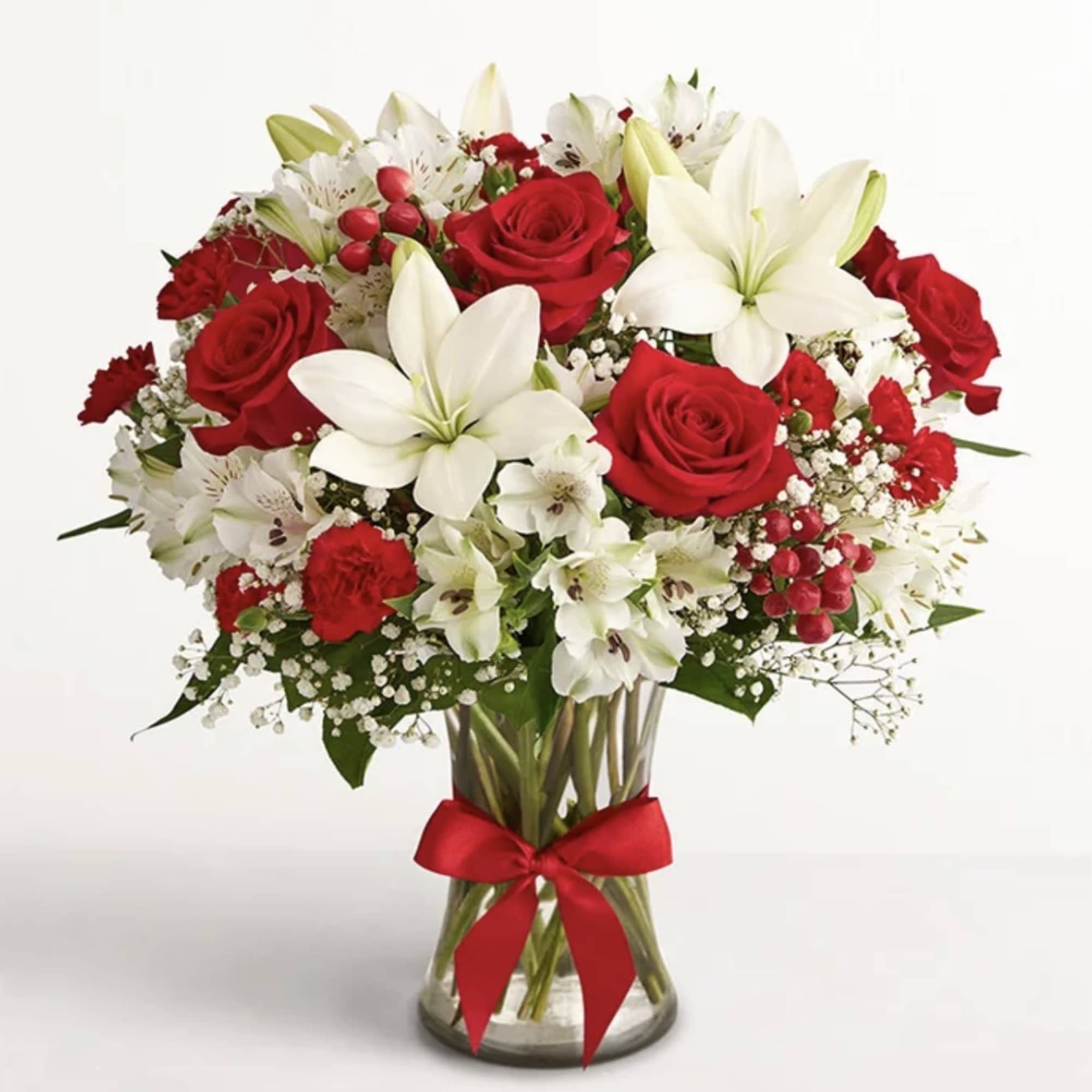 Red roses and white lilies in a glass vase with a red ribbon